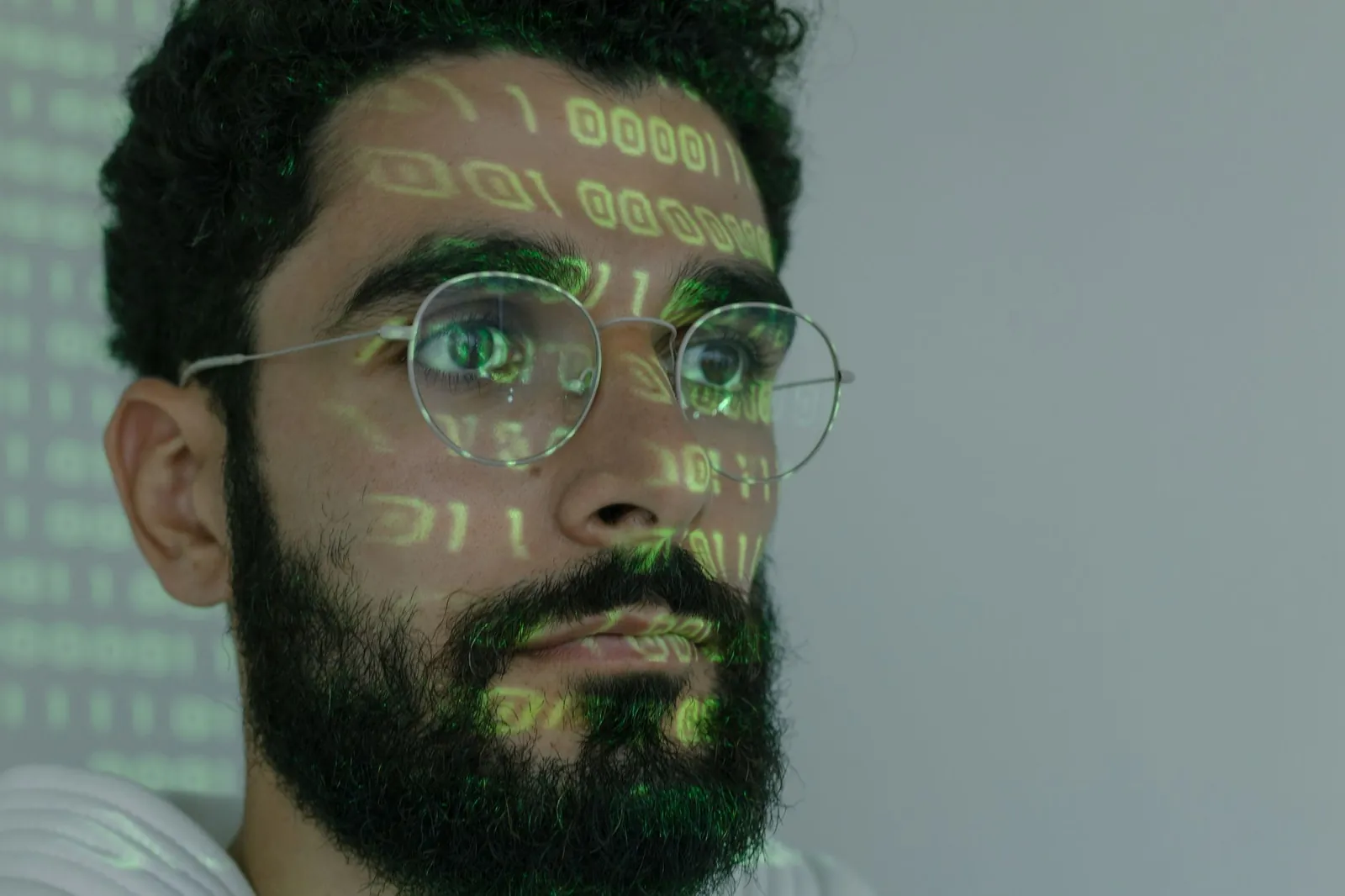 A bearded man with digital binary code projected on his face, symbolizing cybersecurity and technology. Stock photo illustrating LTM's product launched story.