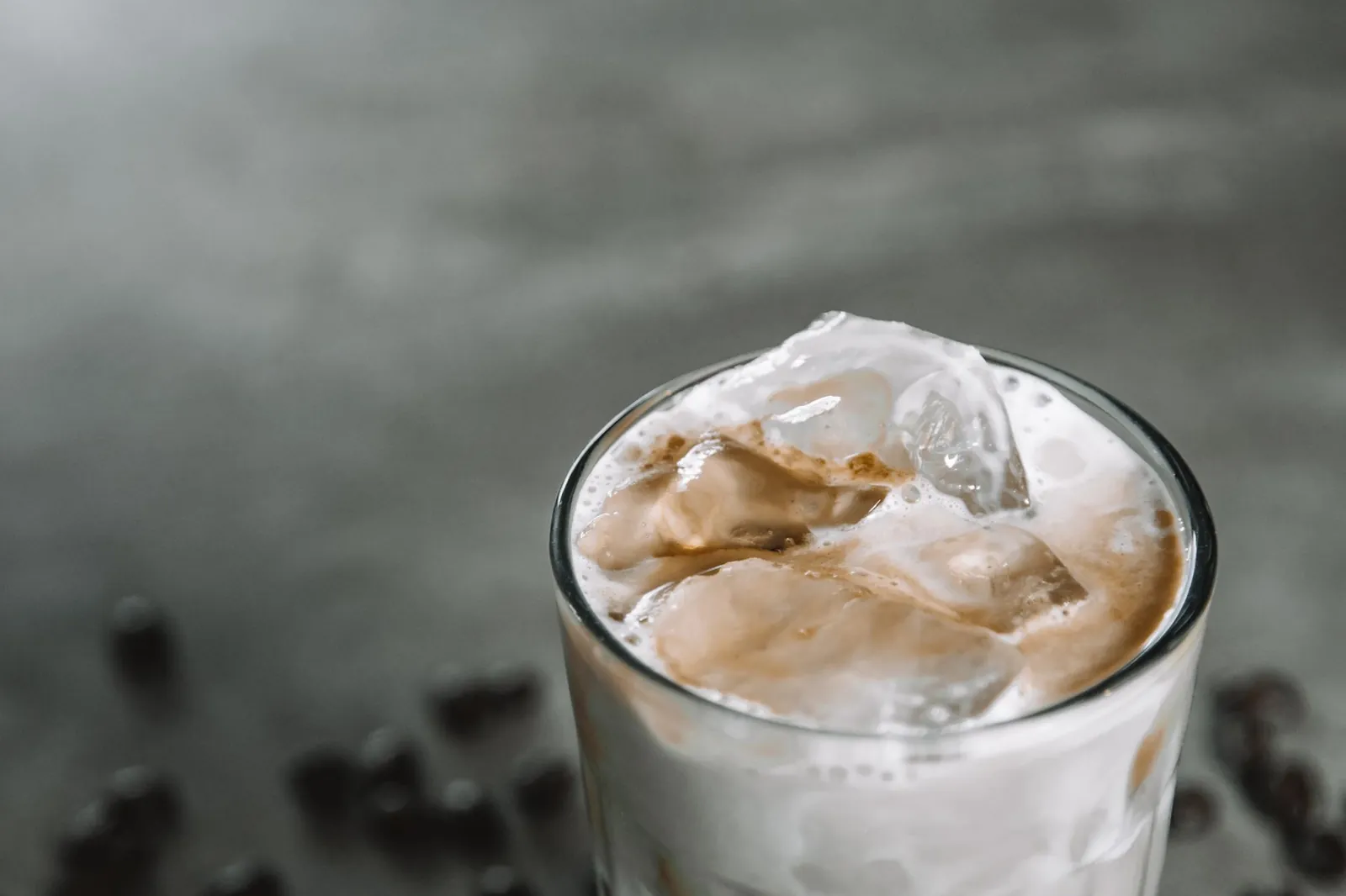 Close-up of a chilled iced coffee with frothy milk and ice cubes in a glass against a muted background. Stock photo illustrating Parag Milk Foods' product launched story.