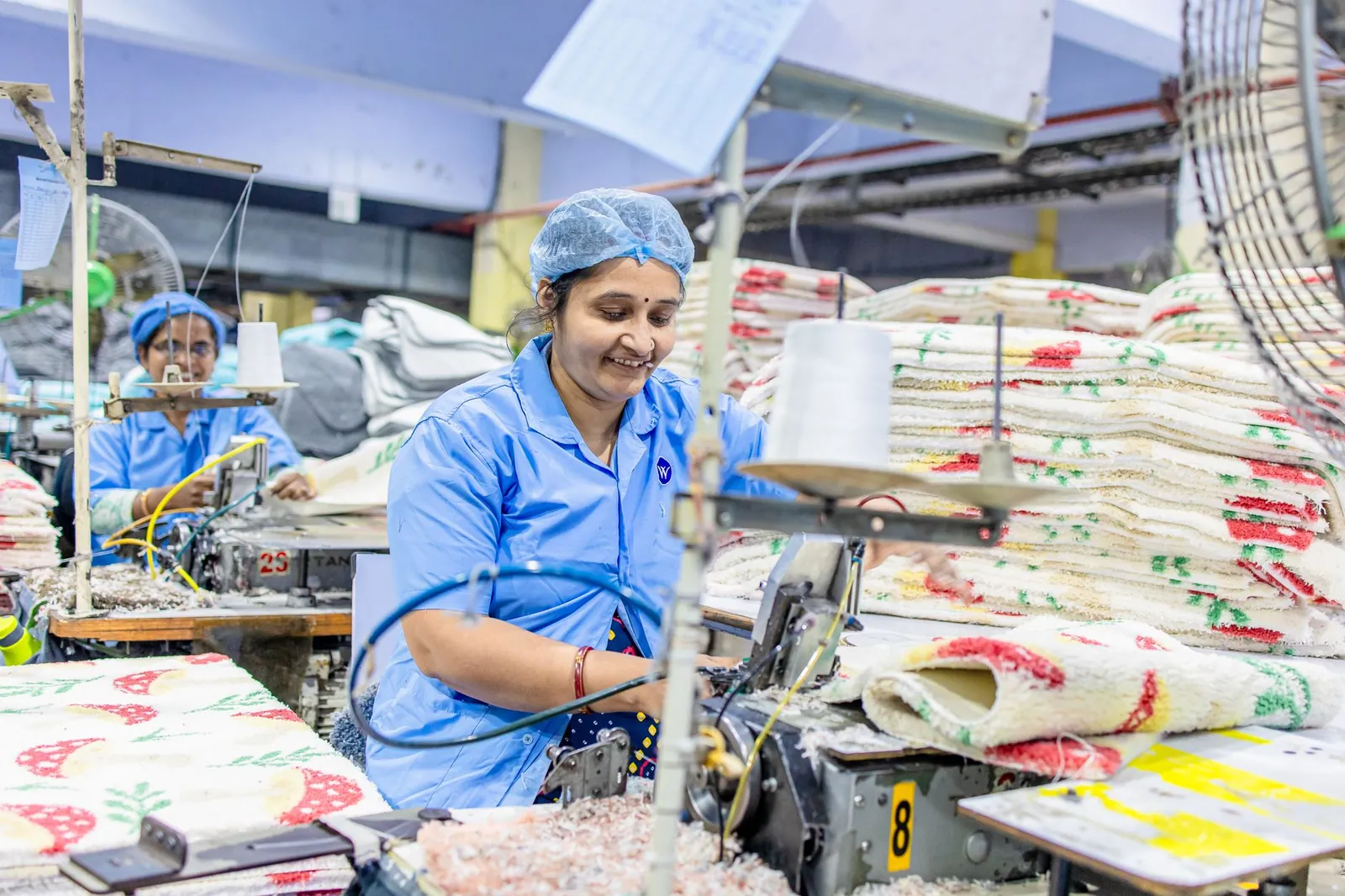 Women operate sewing machines in a vibrant textile factory, producing colorful fabrics. Stock photo illustrating Welspun Living's production started story.