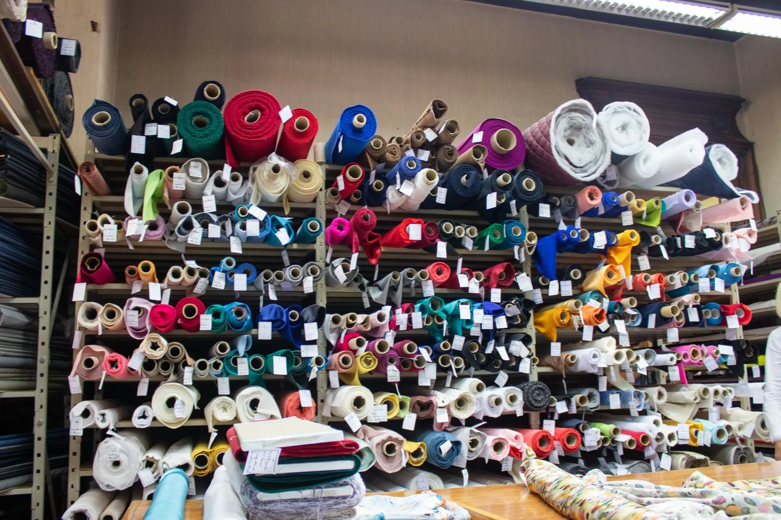 A vibrant display of diverse fabric rolls stacked on shop shelves indoors. Stock photo illustrating Varvee Global's new order story.