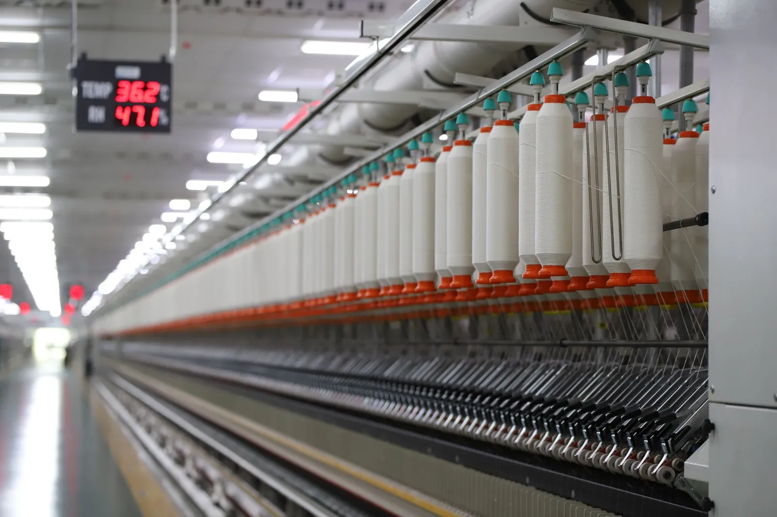 High-tech textile machinery with yarn spools in an Indian factory, demonstrating efficiency. Stock photo illustrating Jindal Worldwide's fund raise story.