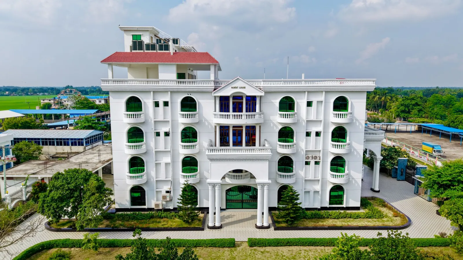 Architectural photo of a beautiful multi-storey white building with green accents and a red roof. Stock photo illustrating Artemis Medicare Services' fund raise story.