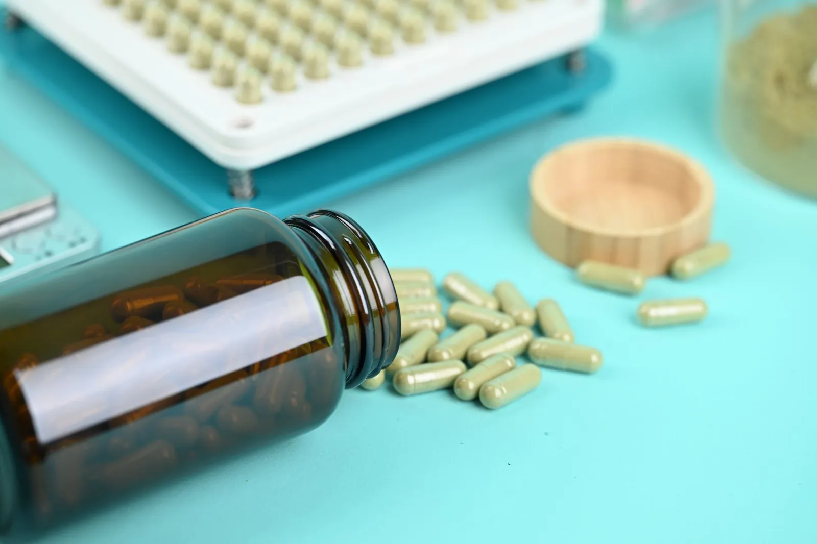 Pills and a capsule filling machine on a blue background, showcasing supplement production. Stock photo illustrating Corona Remedies' earning call story.
