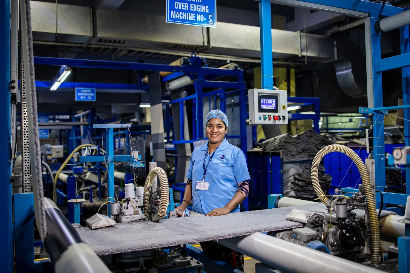 Female textile worker operating machinery in a factory, showcasing industrial work environment. Stock photo illustrating Taurian MPS's fund raise story.