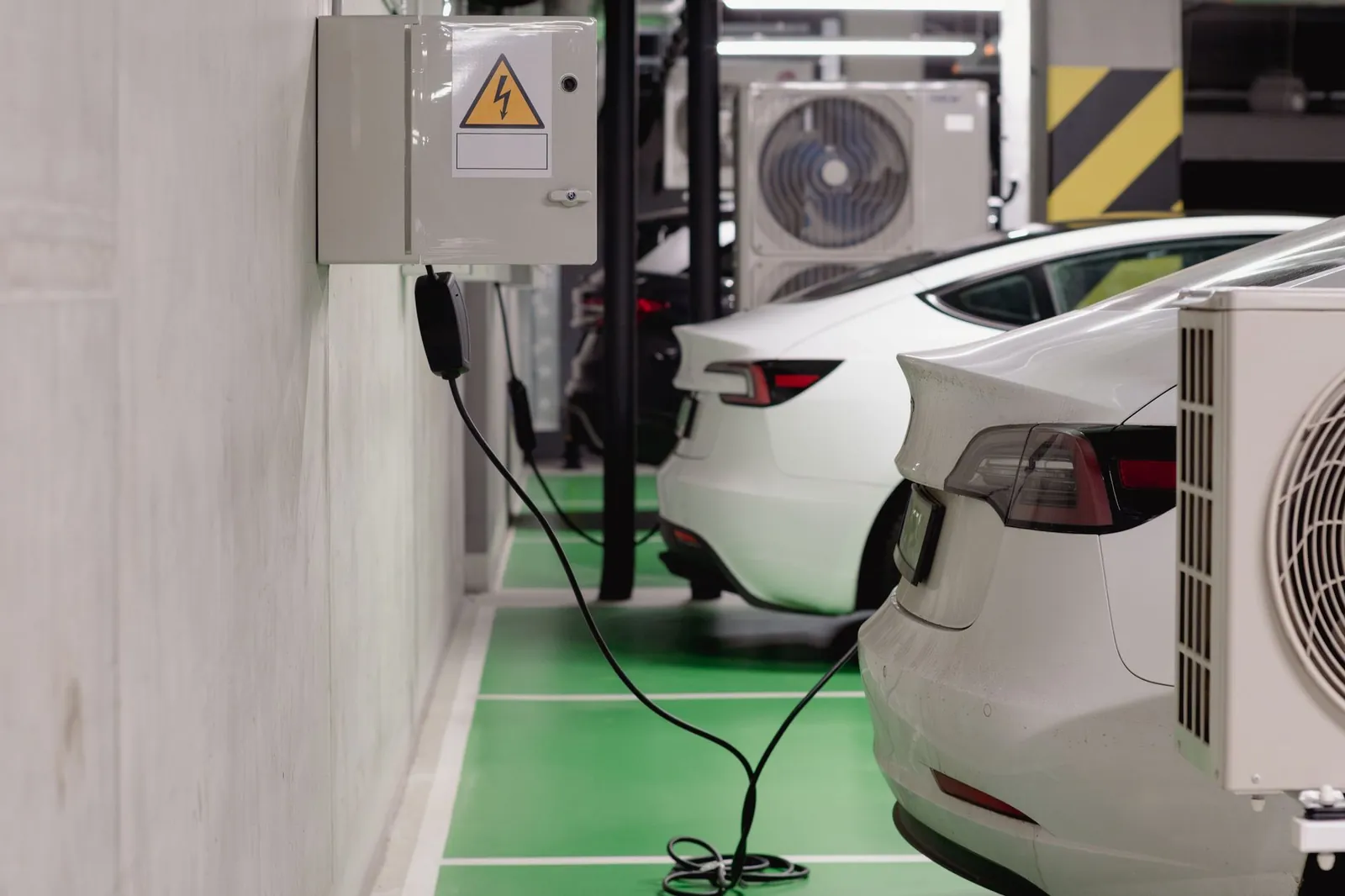 Electric vehicles charging at an indoor station in a modern underground garage. Stock photo illustrating Exicom Tele-Systems' product launched story.