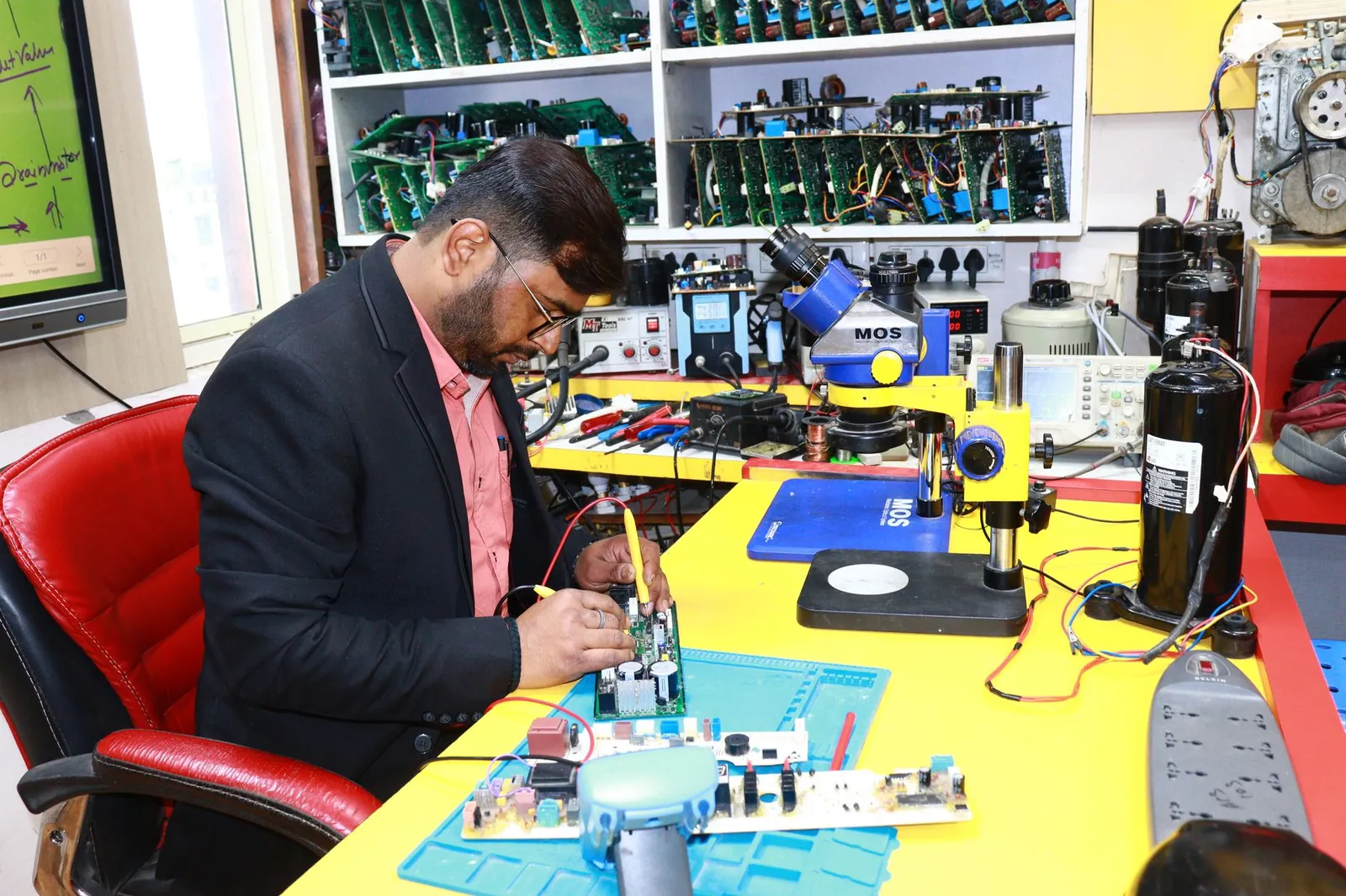 A focused technician repairs a circuit board in a high-tech electronics workshop. Stock photo illustrating Highness Microelectronics' fund raise story.