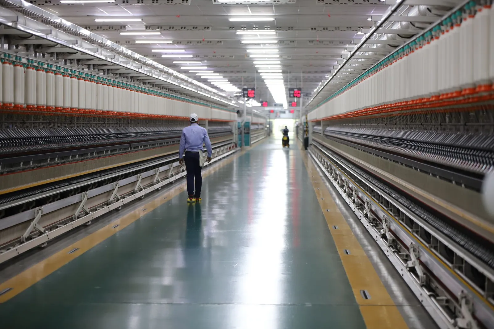 A man walks through a well-lit hallway in a modern industrial textile plant in India. Stock photo illustrating Talbros Engineering's expansion story.