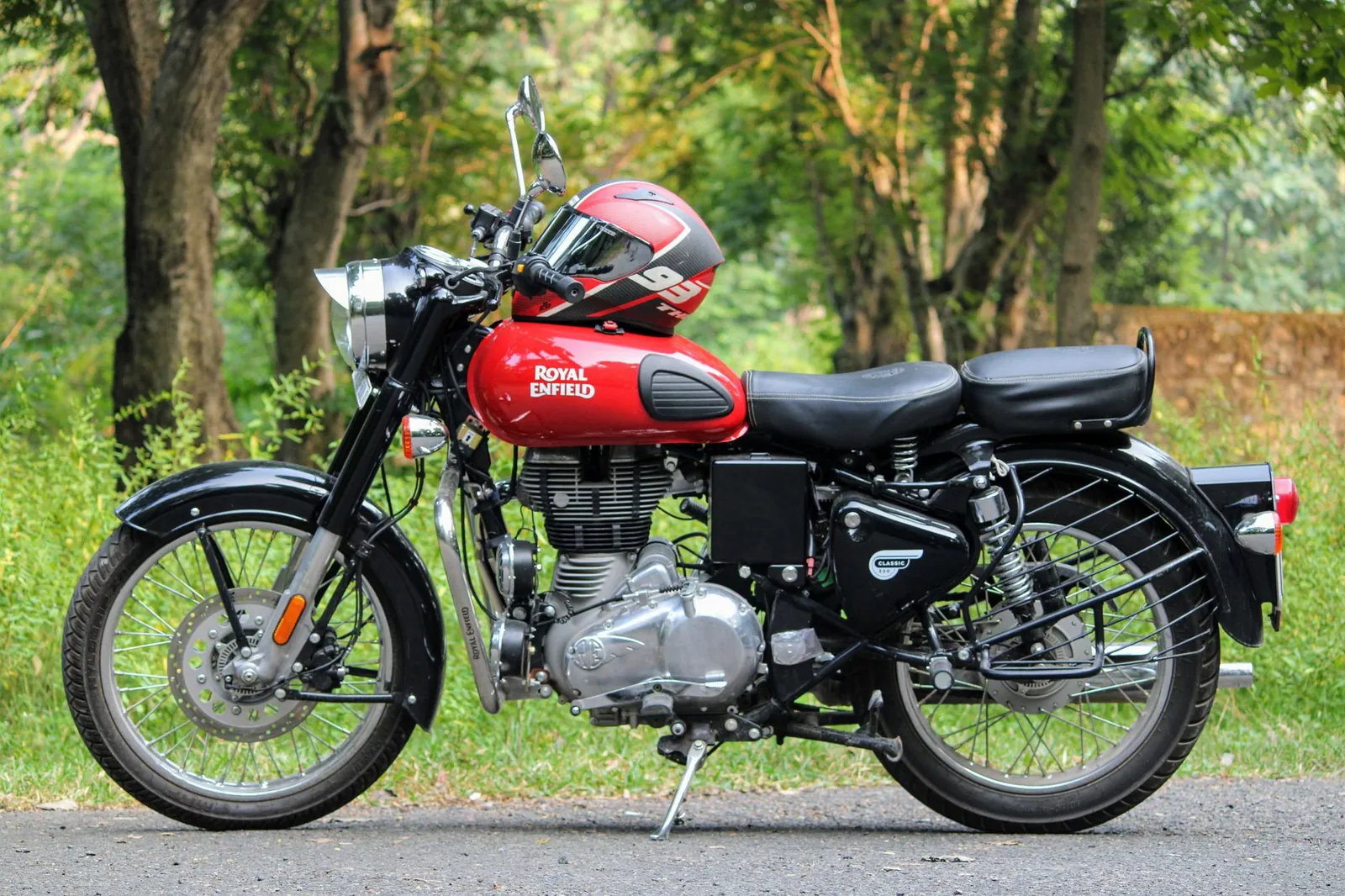 Classic Royal Enfield motorcycle parked on a scenic outdoor road with helmet. Stock photo illustrating Eicher Motors' product launched story.