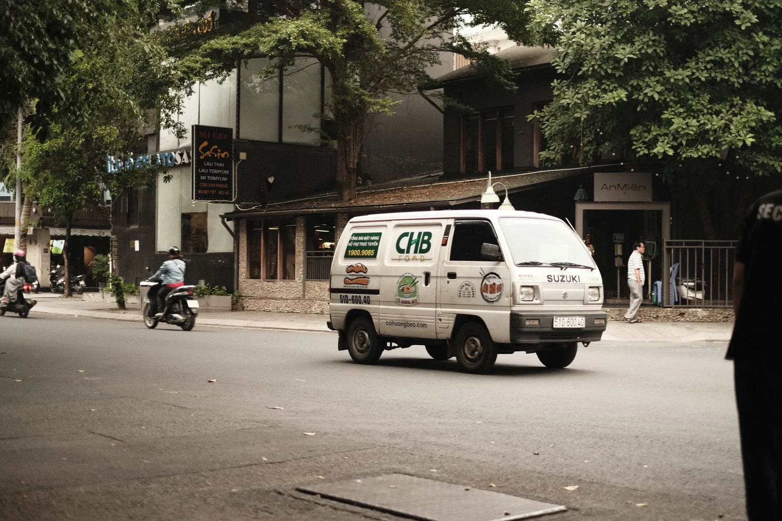 Urban street scene featuring a white Suzuki van and motorcycles in city traffic. Stock photo illustrating Maruti Suzuki India's product launched story.