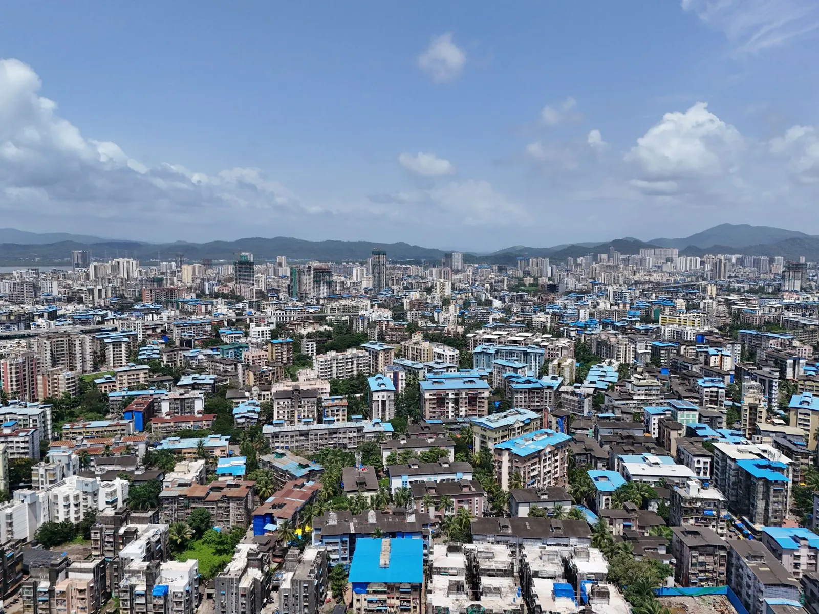 A wide aerial shot of Mumbai's skyline featuring distinctive blue rooftops under a clear sky. Stock photo illustrating Sri Lotus Developers and Realty's earning call story.