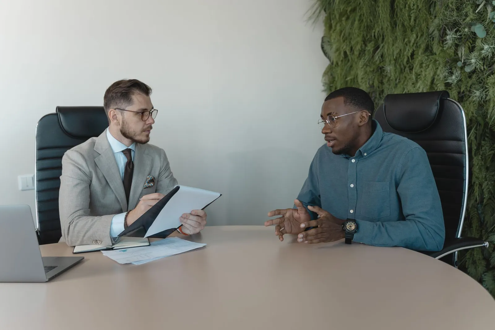 Two businessmen engaged in a discussion during a job interview in a contemporary office environment. Stock photo illustrating Rnit Ai Solutions' new order story.