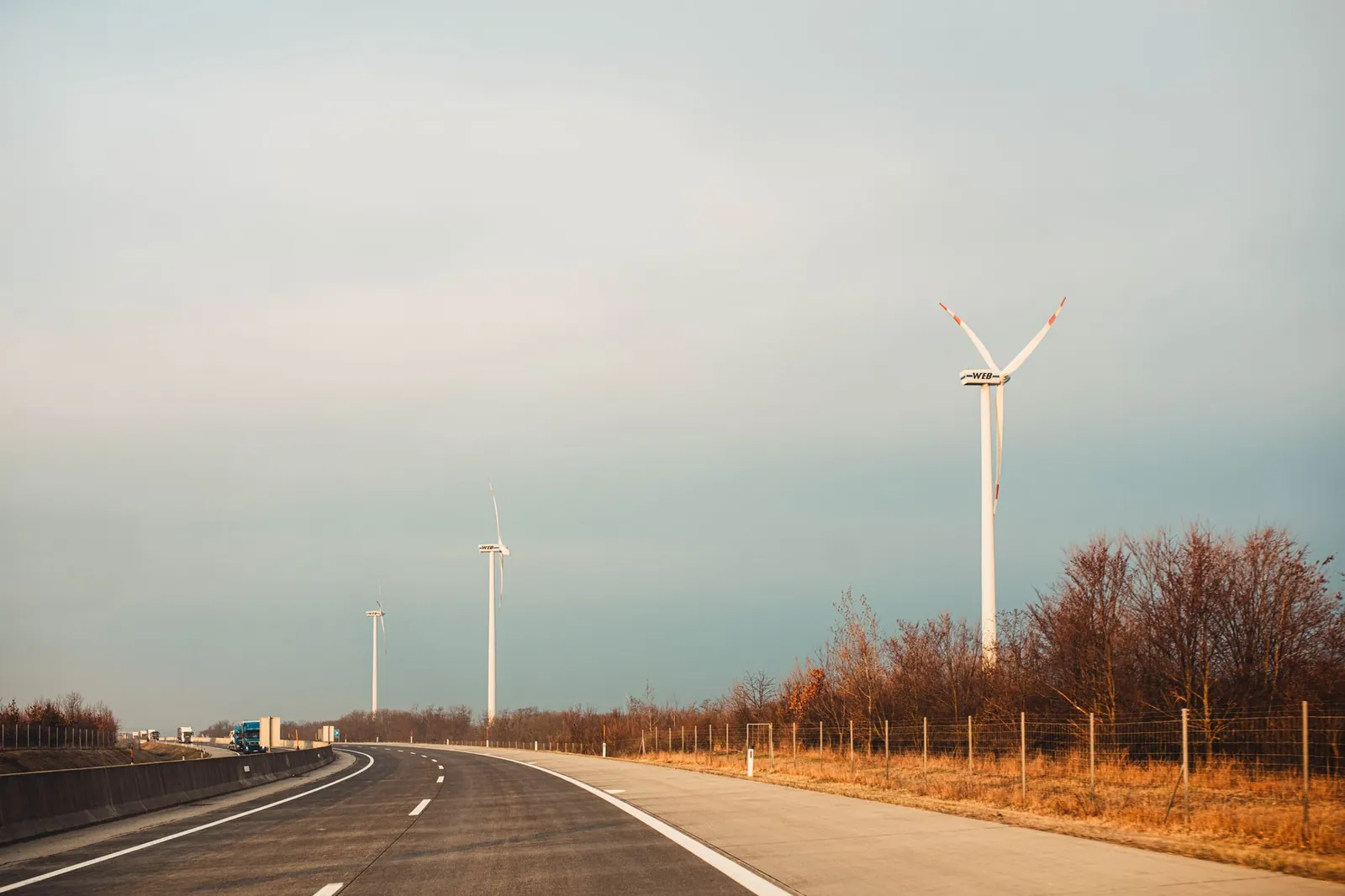 Scenic view of wind turbines by a highway at sunset, showcasing renewable energy. Stock photo illustrating Waaree Energies' earning call story.