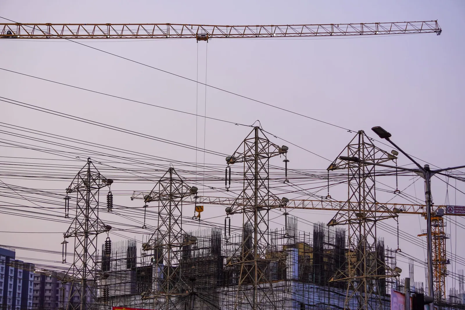 Construction site with cranes and power lines in Mumbai during evening hours. Stock photo illustrating Cemindia Projects' fund raise story.