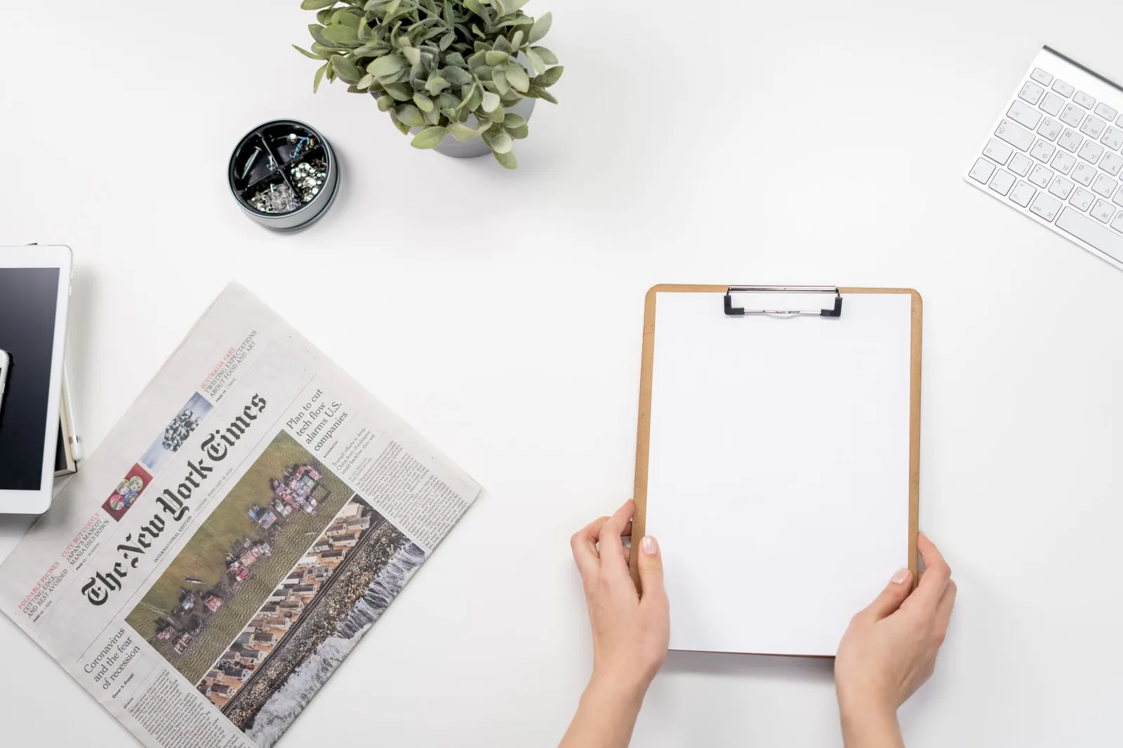Flat lay of a home office desk with a clipboard, newspaper, and accessories. Stock photo illustrating Methodhub Software's product launched story.