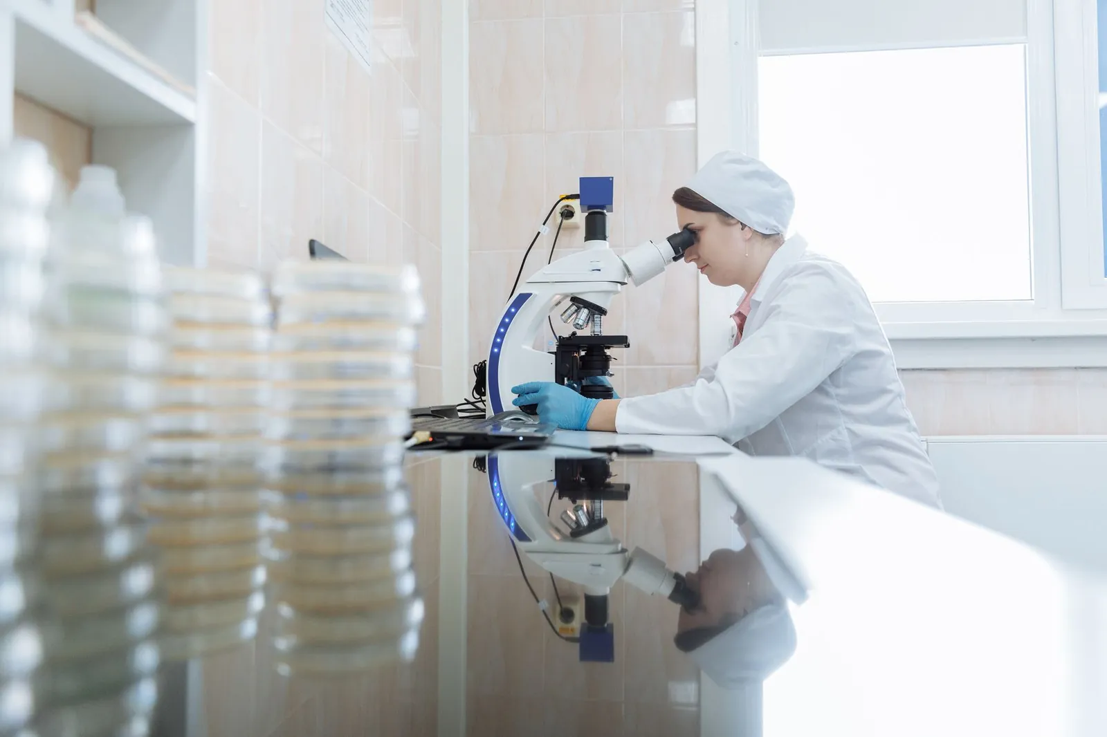 Female scientist using a microscope in a laboratory environment, focusing on research. Stock photo illustrating Godavari Biorefineries' regulatory approval story.