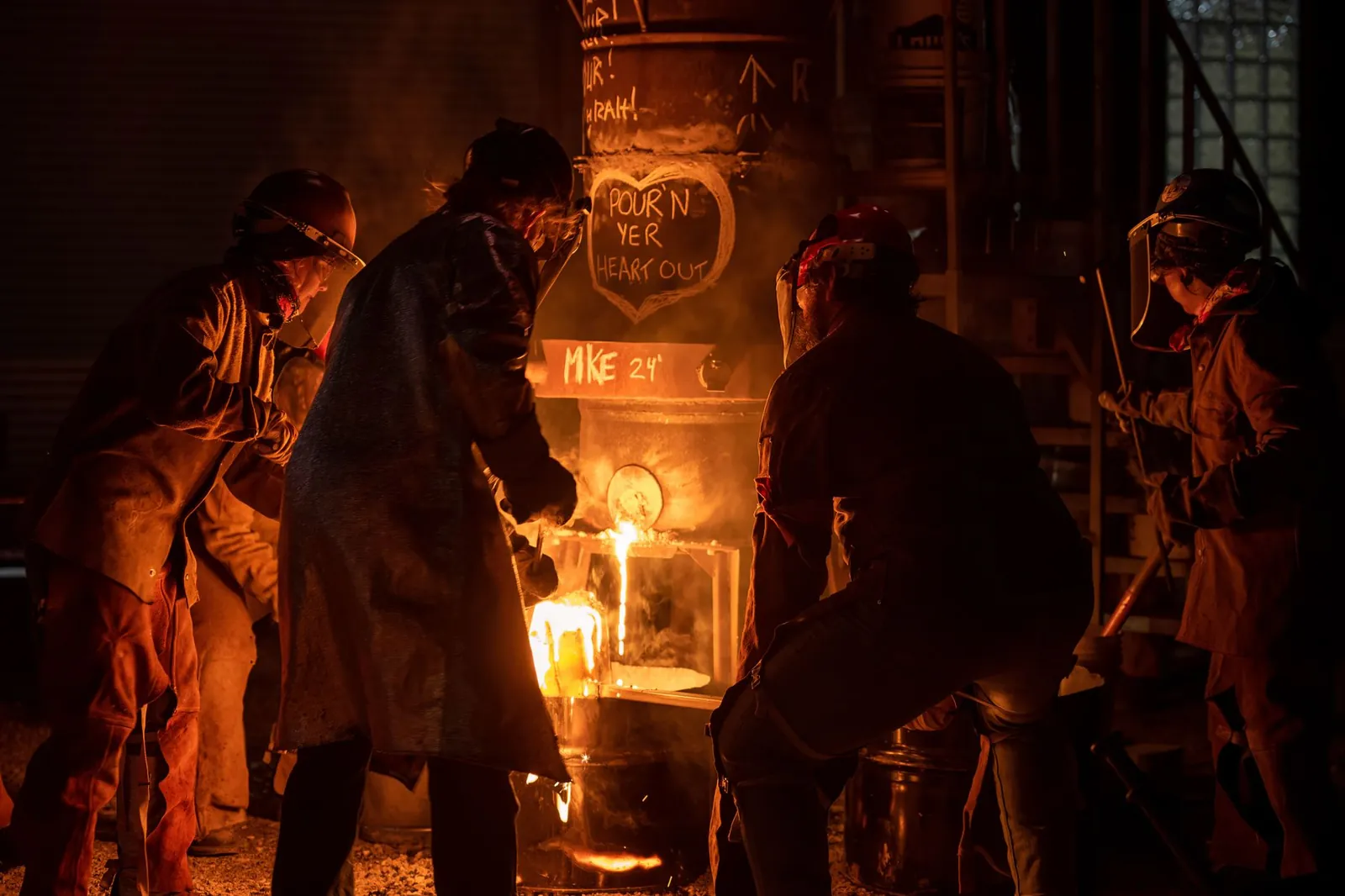 Metalworkers in Milwaukee pour molten metal from a furnace at night, creating an industrial scene. Stock photo illustrating National Aluminium Company's partnership story.