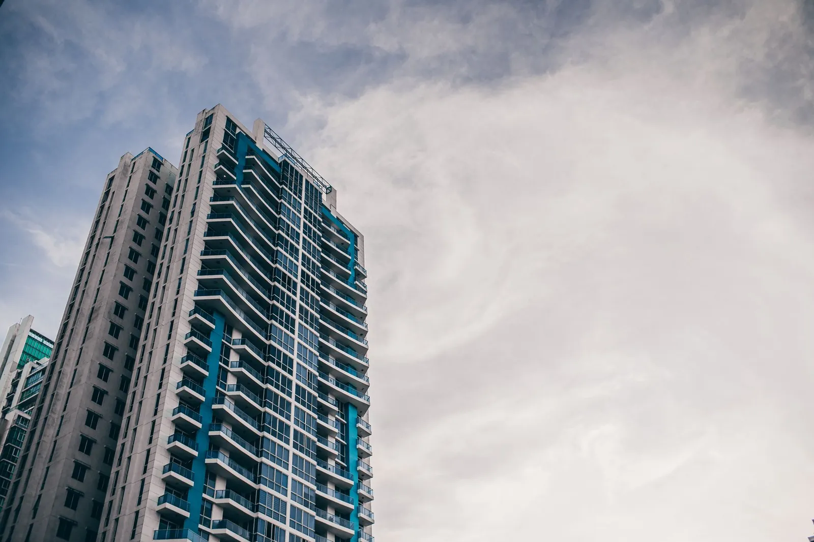 High-rise building with modern architecture reaching into a cloudy sky. Stock photo illustrating Agi Infra's regulatory approval story.