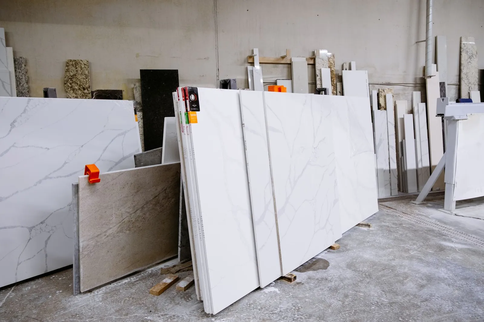 Wide view of granite and marble slabs neatly arranged in a factory setting, showcasing variety and texture. Stock photo illustrating Nitco's new order story.