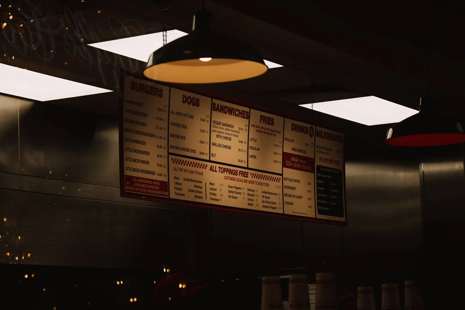 Dimly lit fast food restaurant interior with visible menu and ceiling lighting. Stock photo illustrating Westlife Foodworld's promoter buying story.