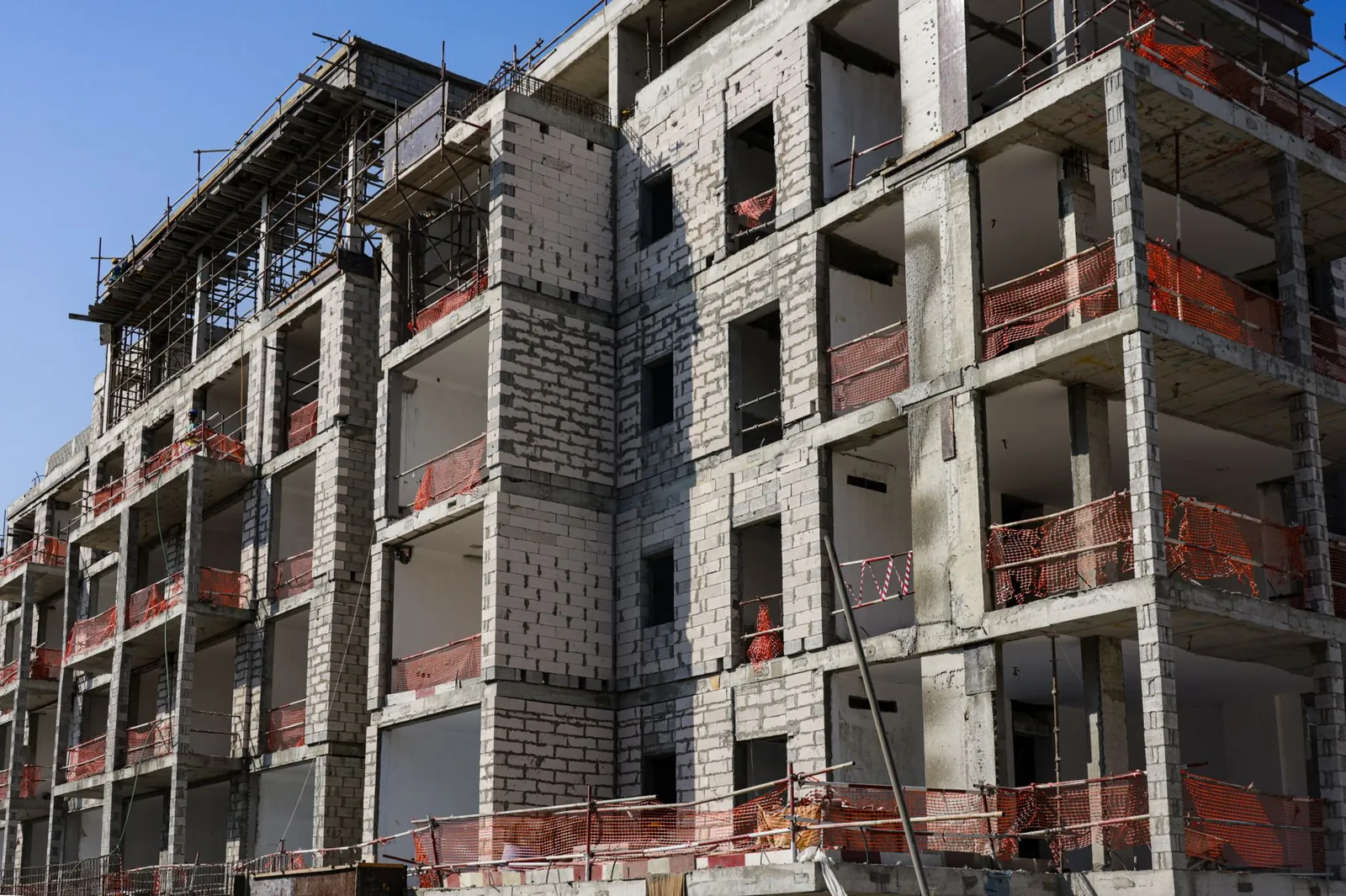 A modern multi-story apartment building under construction with scaffolding and safety netting. Stock photo illustrating NBCC (India)'s new order story.