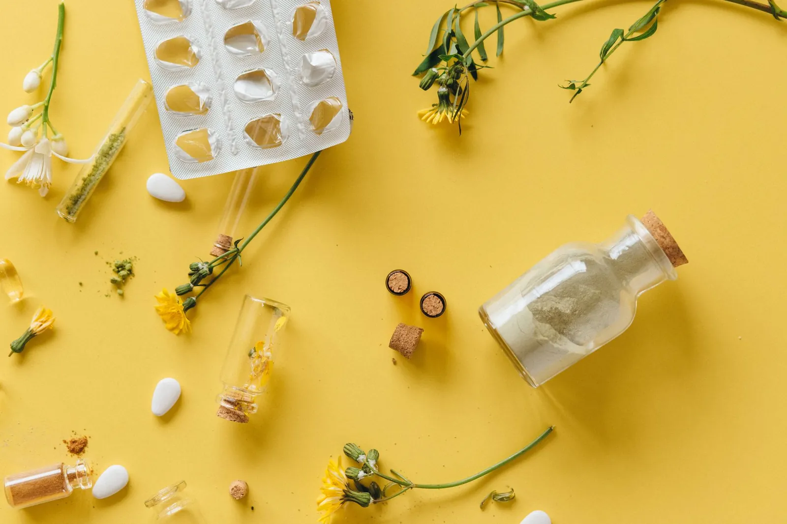 Flat lay of herbal medicines and glass containers on a yellow background. Stock photo illustrating Jeena Sikho Lifecare's product launched story.