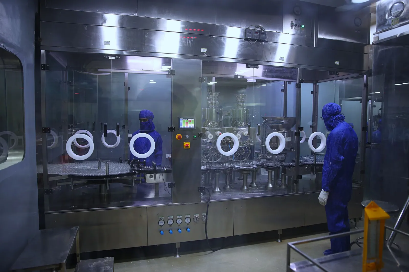 Workers in protective gear inside a sterile pharmaceutical manufacturing plant in Rawalpindi, Pakistan. Stock photo illustrating Jeena Sikho Lifecare's product launched story.