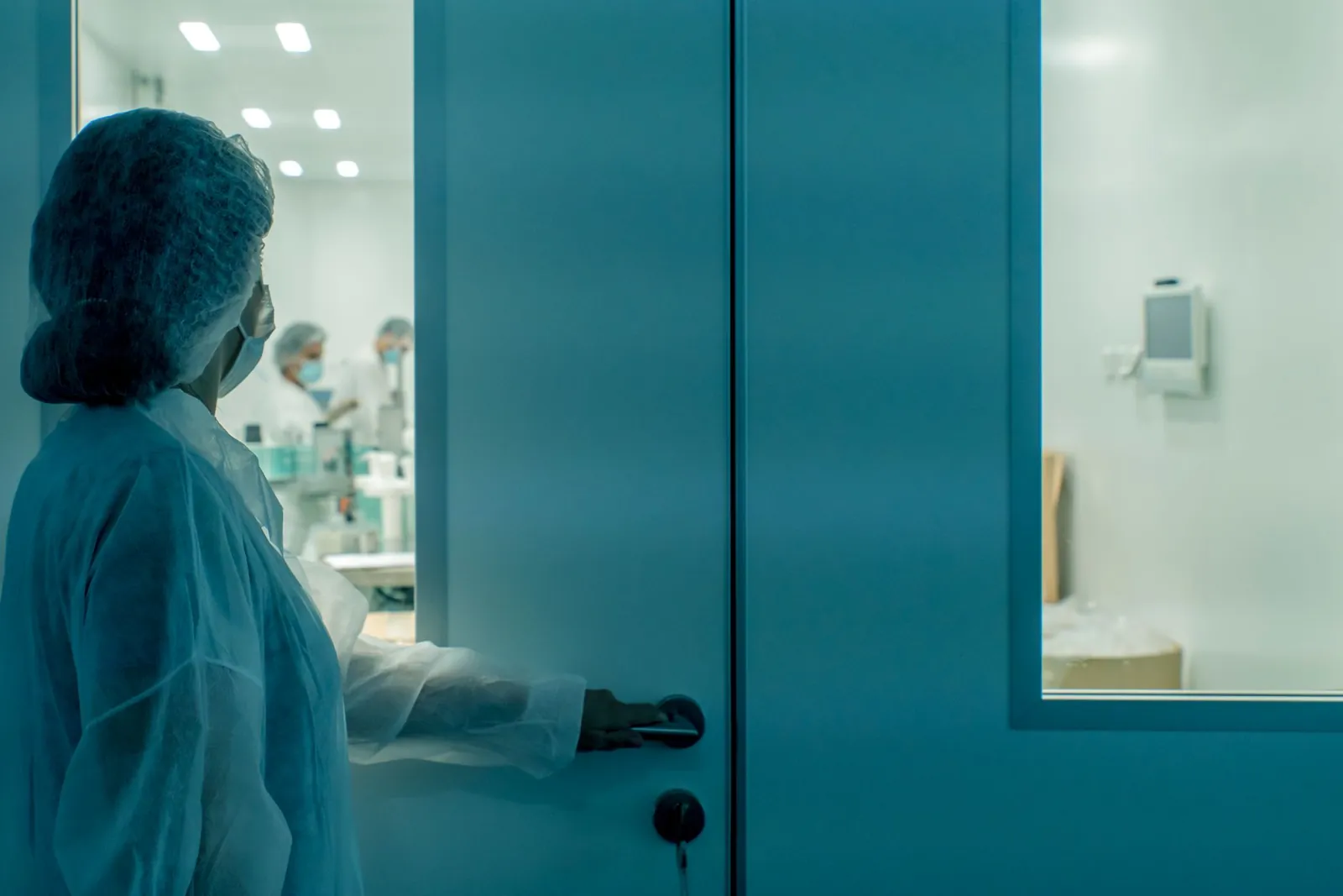 A scientist in protective gear enters a sterile laboratory environment, ensuring cleanliness. Stock photo illustrating Shilpa Medicare's production started story.
