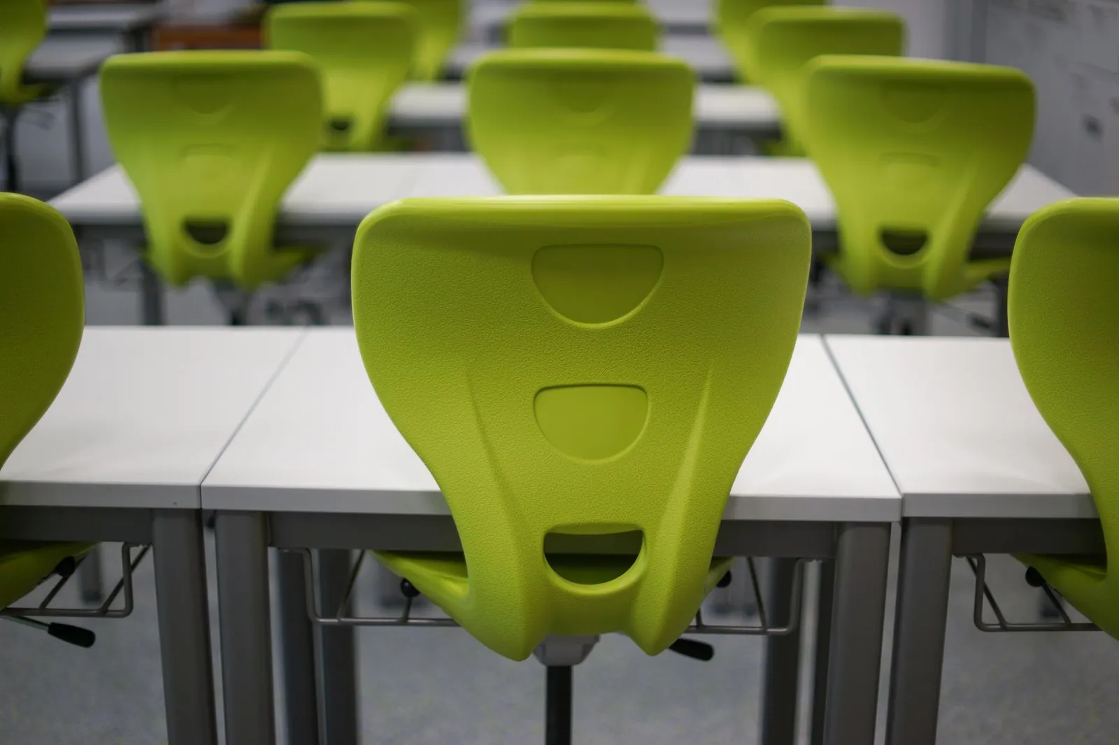 An empty modern classroom featuring rows of vibrant green plastic chairs and white desks. Stock photo illustrating NIIT's product launched story.