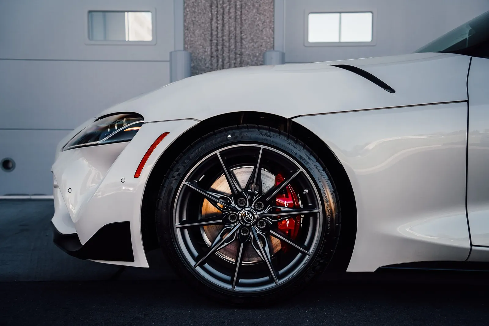 Close-up of a white sports car wheel with sleek alloy rims and brake calipers. Stock photo illustrating Wheels India's fund raise story.