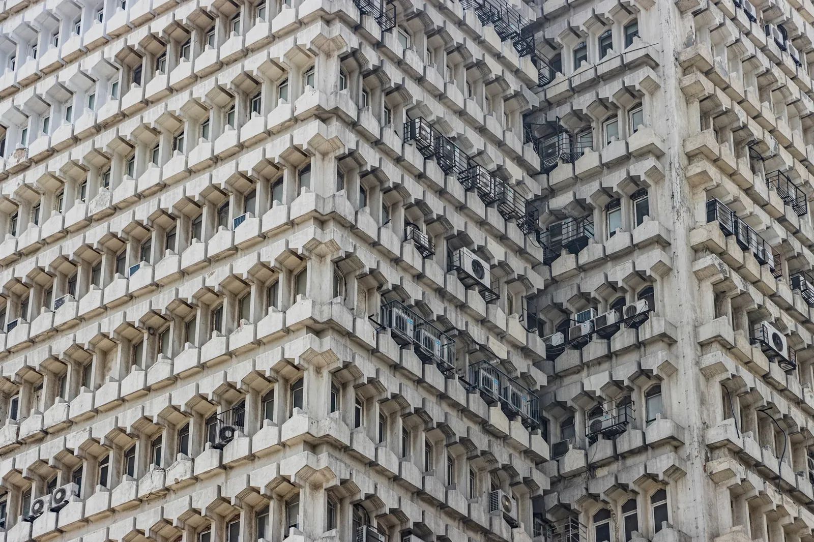 Detailed view of an abstract brutalist building facade in New Delhi, showcasing architectural symmetry and aesthetic appeal. Stock photo illustrating Knowledge Realty Trust's earning call story.
