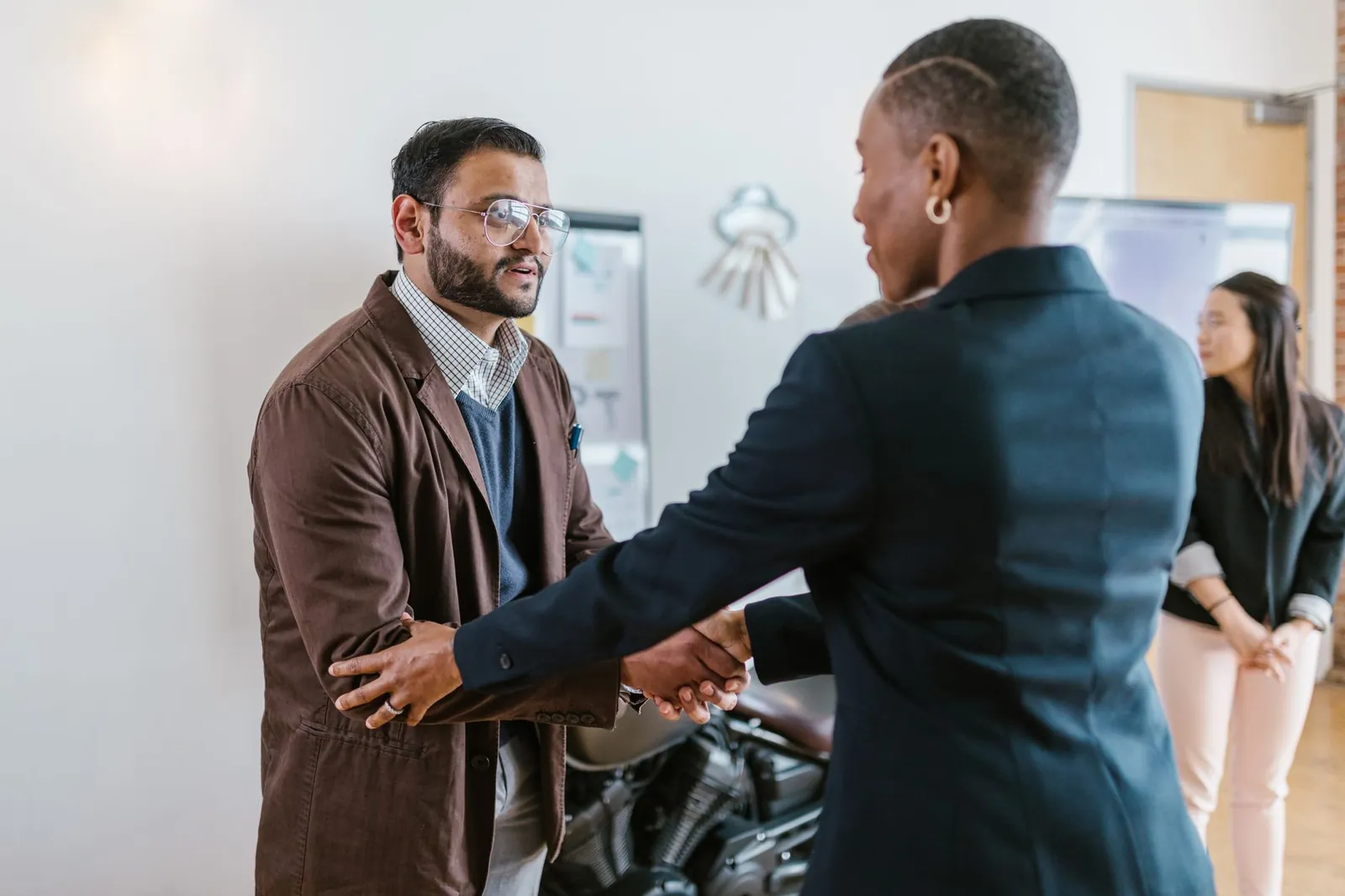 Business professionals greeting with a handshake in an office setting, promoting teamwork and cooperation. Stock photo illustrating Piramal Finance's fund raise story.