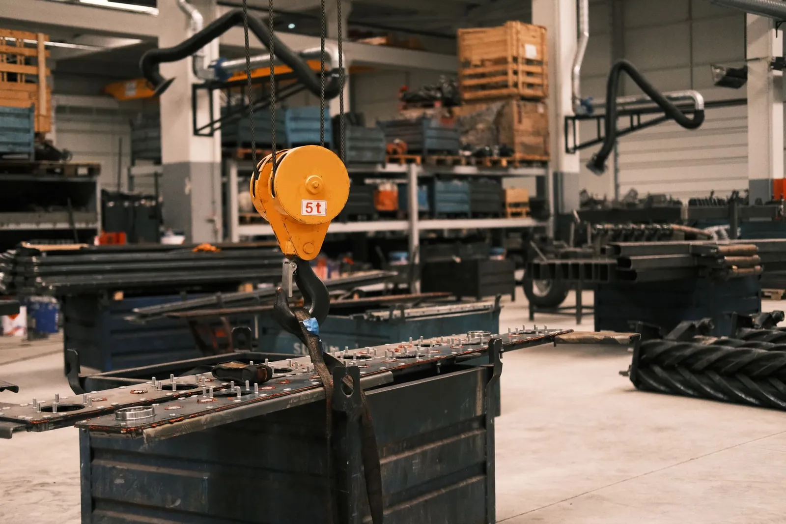 Close-up of a yellow industrial crane hook in a manufacturing workshop in Konya, Türkiye, showcasing metalwork. Stock photo illustrating TIL's fund raise story.