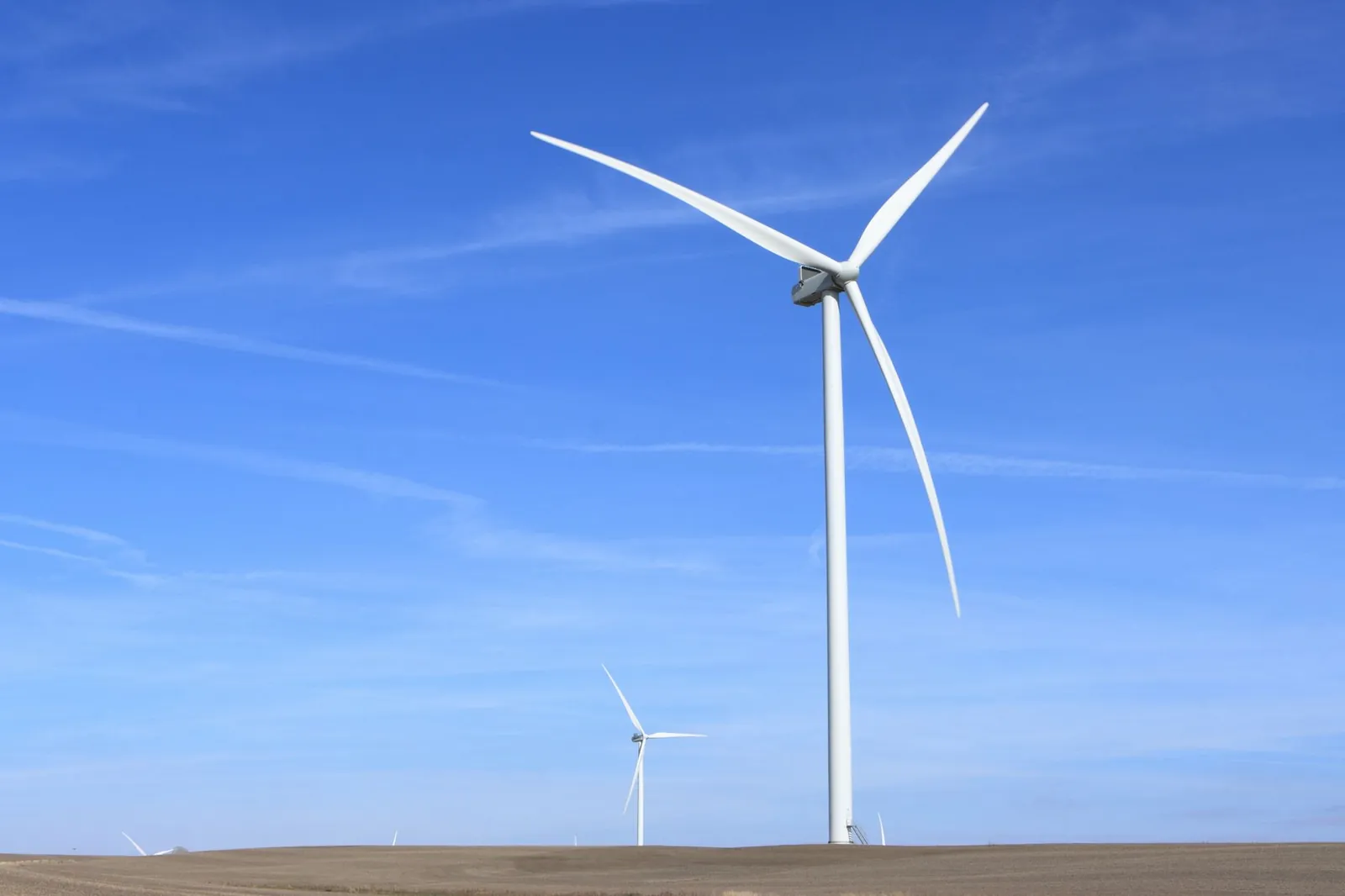 Wind turbines under a clear blue sky symbolize clean energy and sustainability. Stock photo illustrating JSW Energy's production started story.