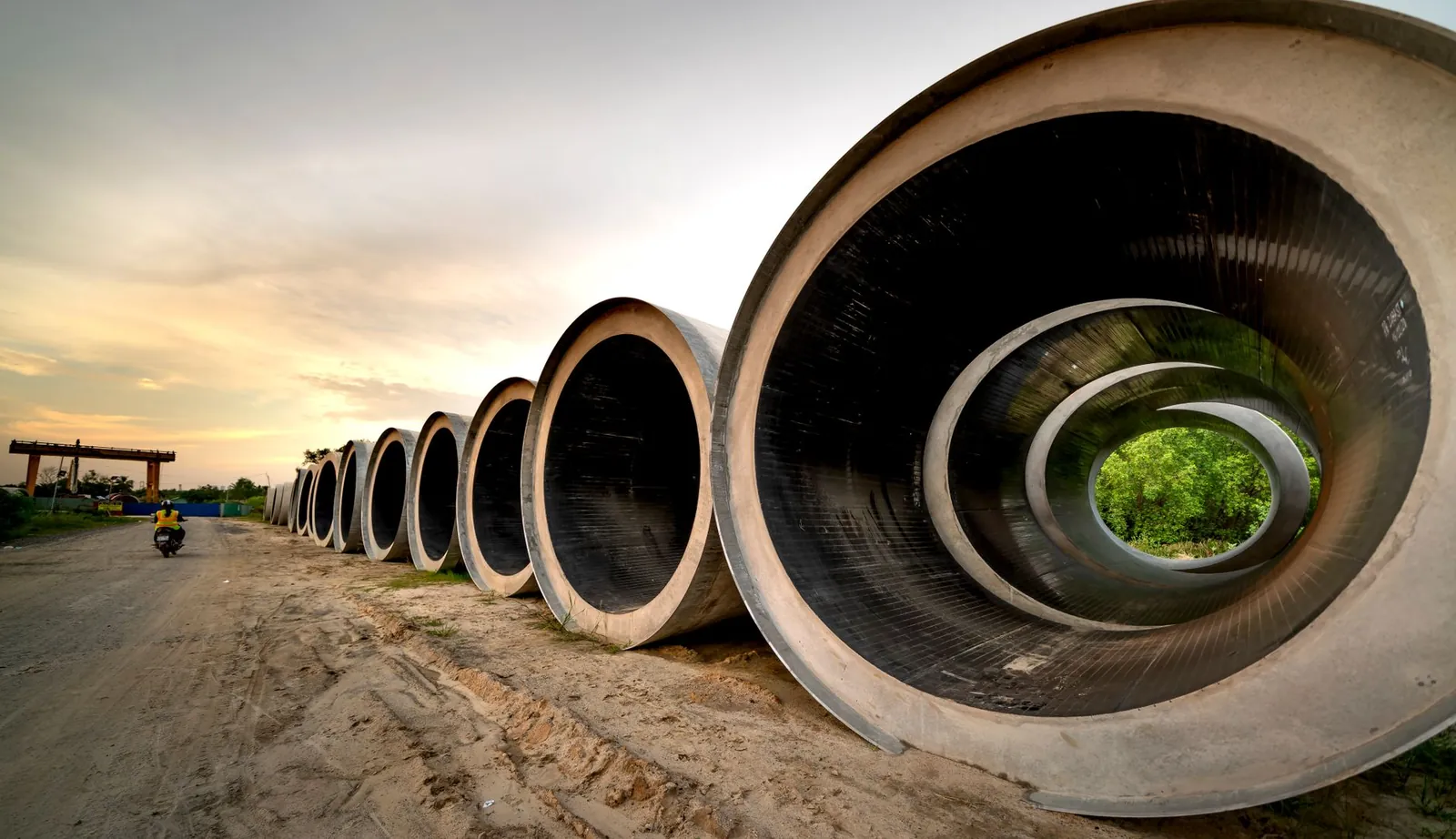 Massive concrete pipes aligned at a construction site during sunset, showcasing an industrial landscape. Stock photo illustrating EMS's new order story.
