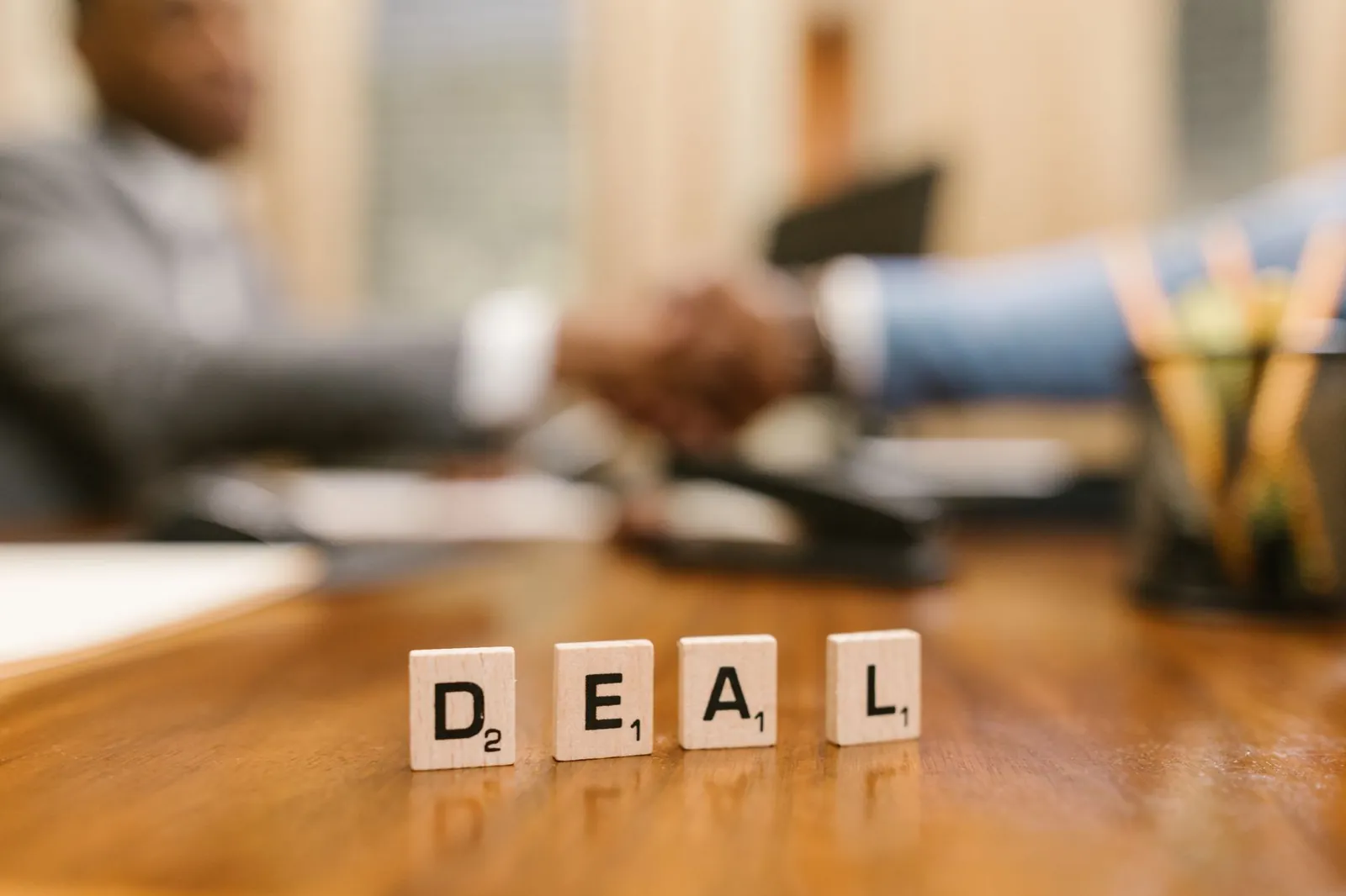 Close-up of Scrabble tiles spelling 'deal' with a handshake in the background. Stock photo for the ALFA News guide: Bulk Deal vs Block Deal: The Definitive SEBI 2026 Guide.