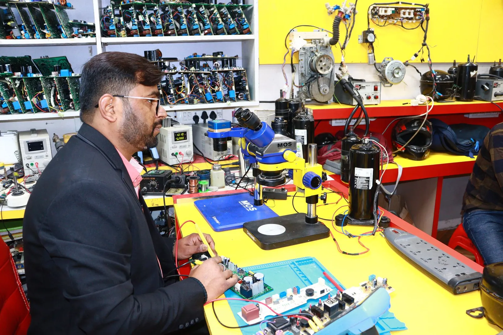 A man in Delhi working in an electronics lab with tools and components. Stock photo illustrating Spectrum Electrical Industries' fund raise story.