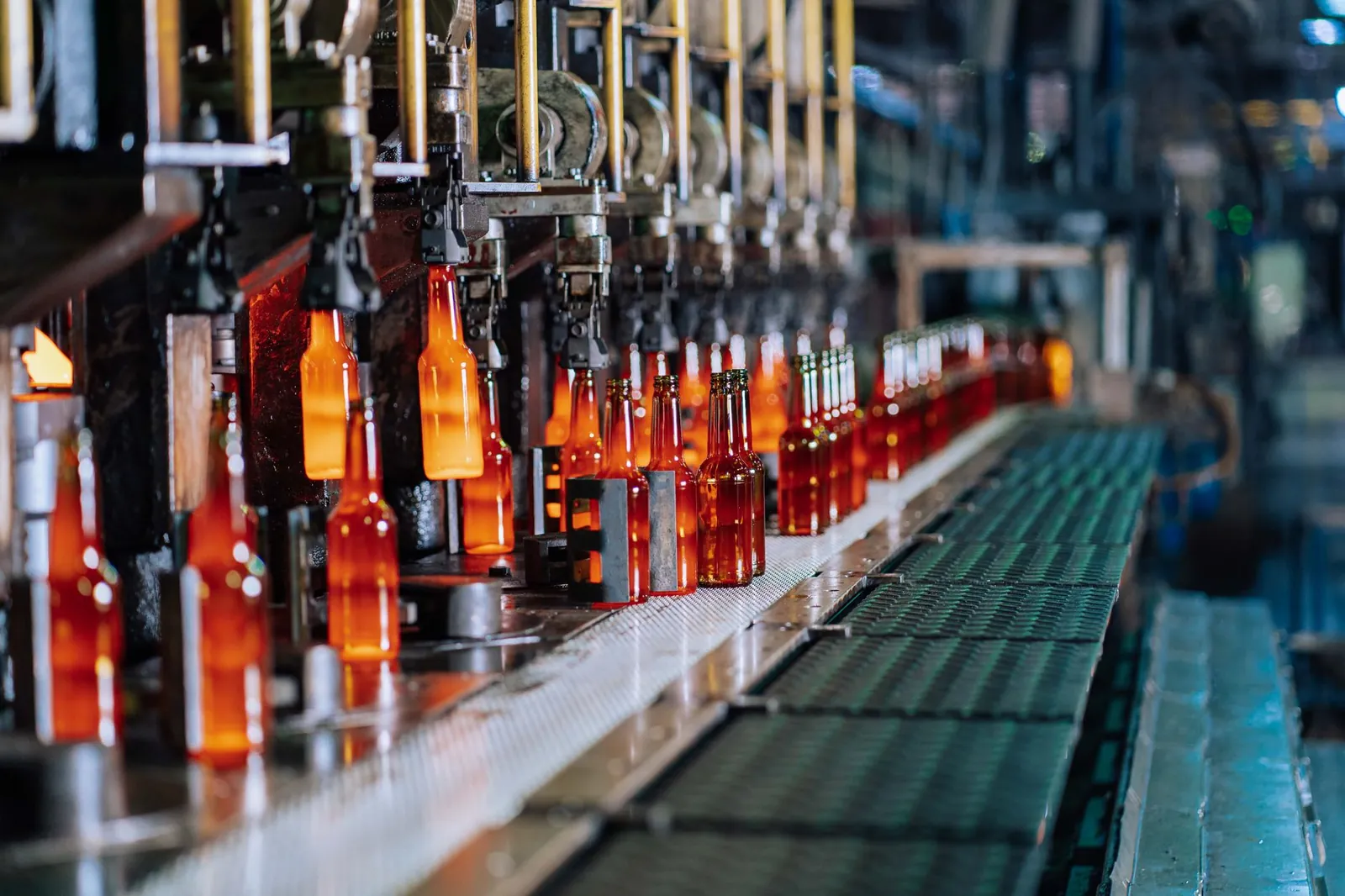Glass bottles being manufactured on an automated production line in a factory. Stock photo illustrating Borosil Scientific's expansion story.