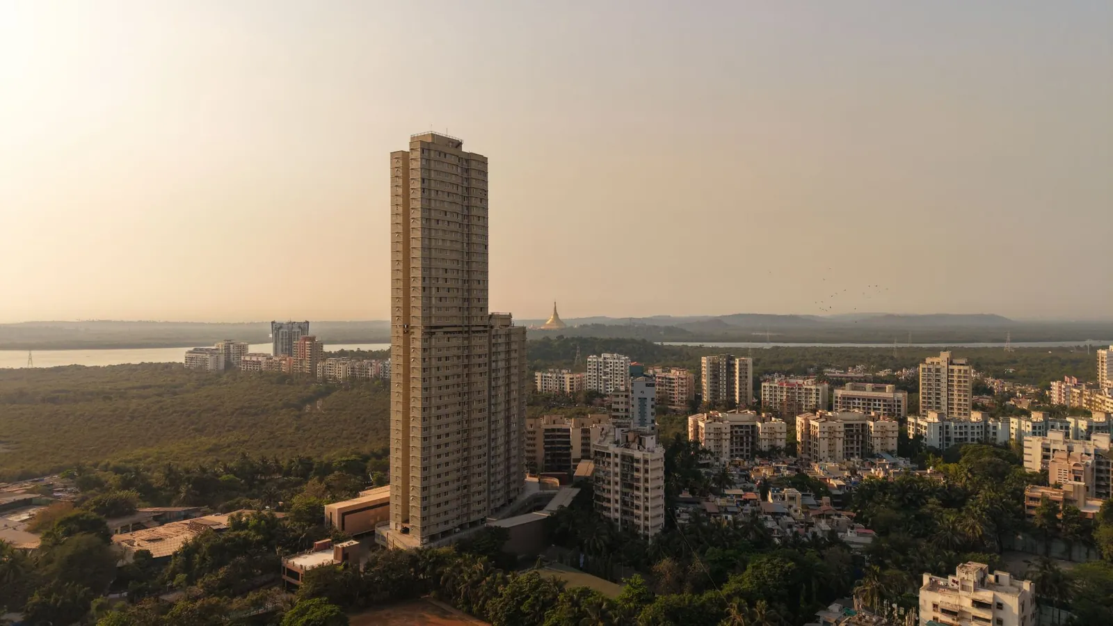 A captivating aerial shot of Mumbai's skyline with tall buildings and lush greenery at sunset. Stock photo illustrating Sri Lotus Developers and Realty's earning call story.