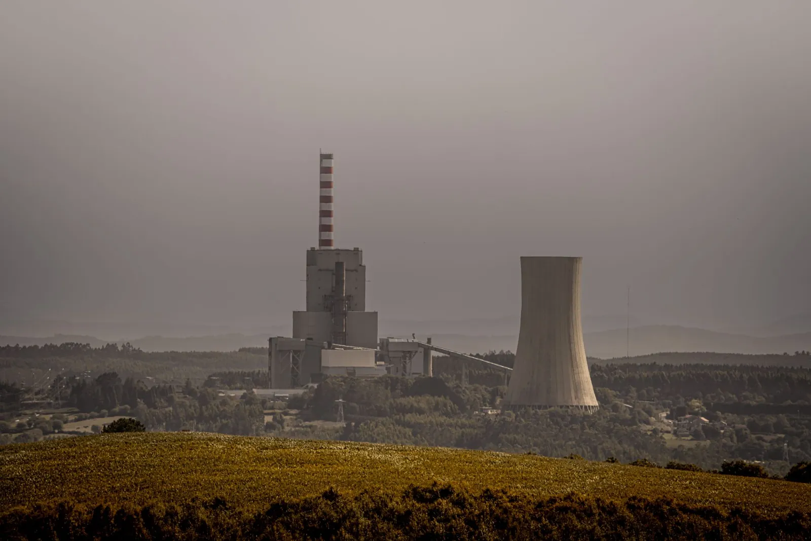 A coal-fired power plant emits smoke on an overcast day, highlighting energy and environmental issues. Stock photo illustrating Adani Power's regulatory approval story.