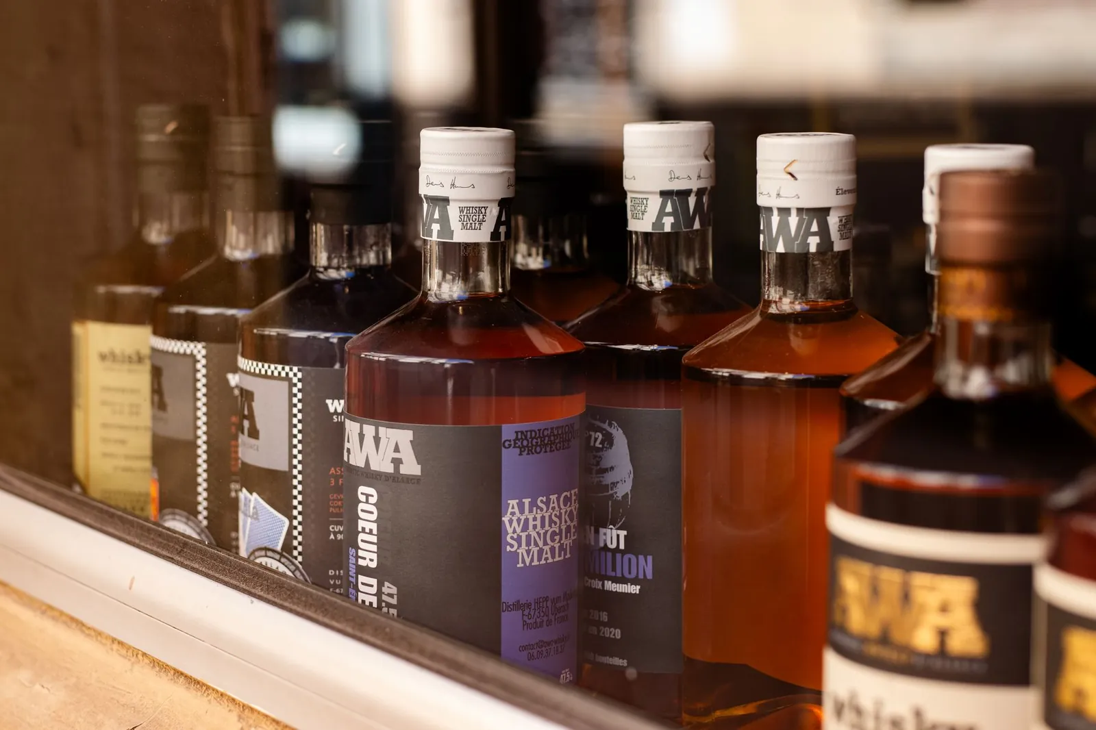 Close-up of Alsace whisky bottles displayed in a Colmar store window. Stock photo illustrating Piccadily Agro Industries' product launched story.