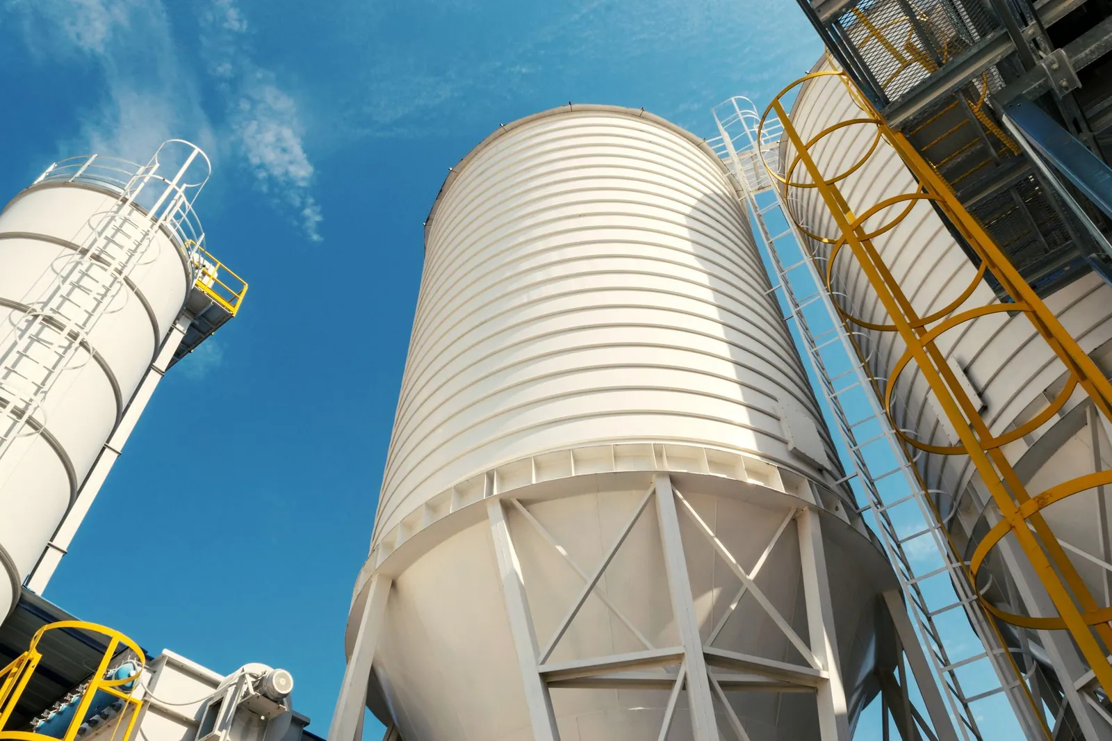Wide-angle view of industrial silos with clear blue sky, captured during daytime, showcasing modern industry. Stock photo illustrating VA Tech Wabag's new order story.
