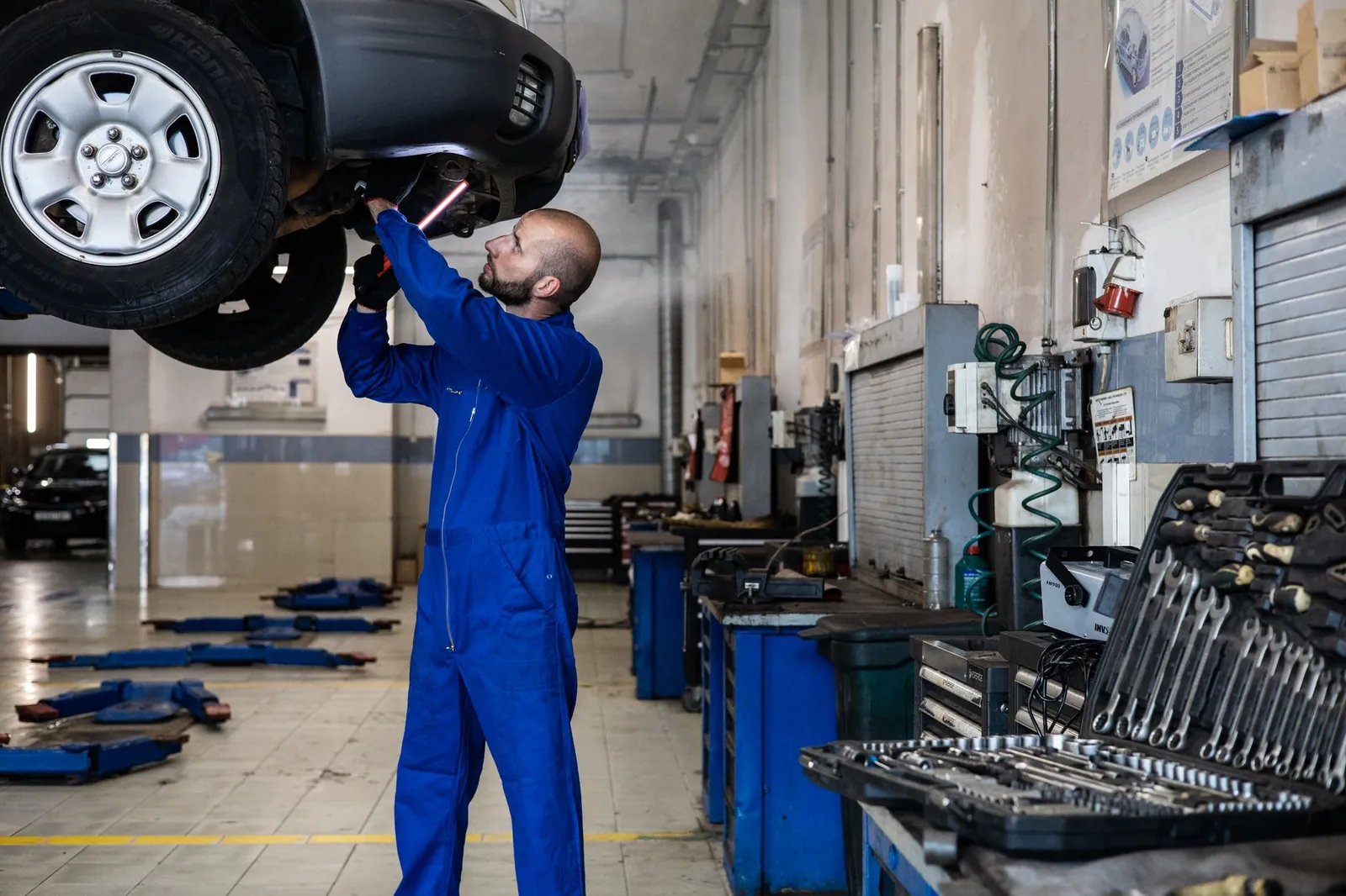 Mechanic inspecting a raised car in an auto workshop for maintenance and repair services. Stock photo illustrating Coforge's product launched story.
