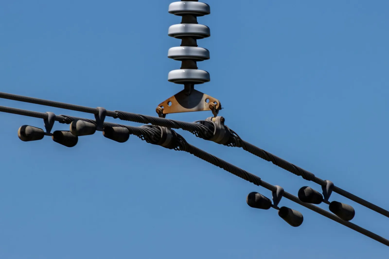 Detailed view of overhead power lines with blue sky background. Ideal for energy themes. Stock photo illustrating Diamond Power Infrastructure's new order story.