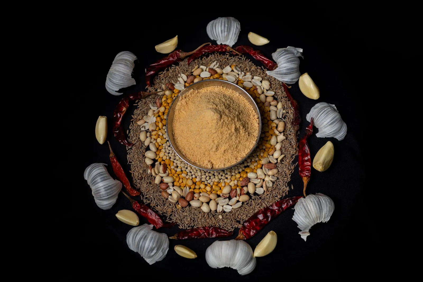 Top view of traditional Indian spices and masala surrounded by garlic and chilies on a dark background. Stock photo illustrating Orkla India's product launched story.