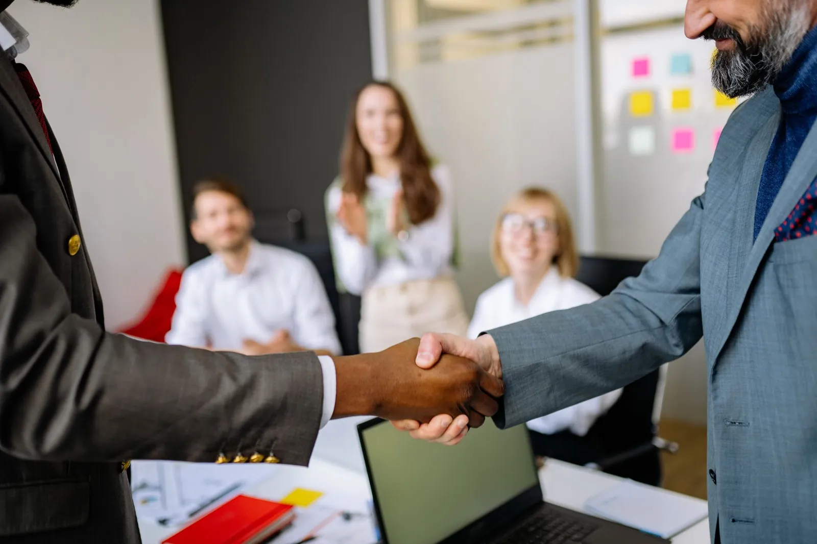 Close-up of a handshake between colleagues in a professional office setting, emphasizing teamwork and agreement. Stock photo illustrating Praruh Technologies' partnership story.