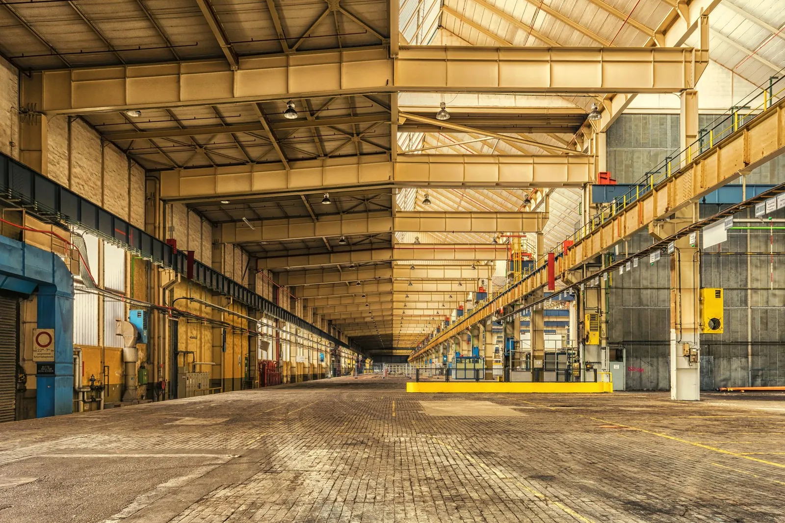 Expansive interior of an industrial warehouse showing steel beams, high ceilings, and ample space. Stock photo illustrating JSW Steel's expansion story.