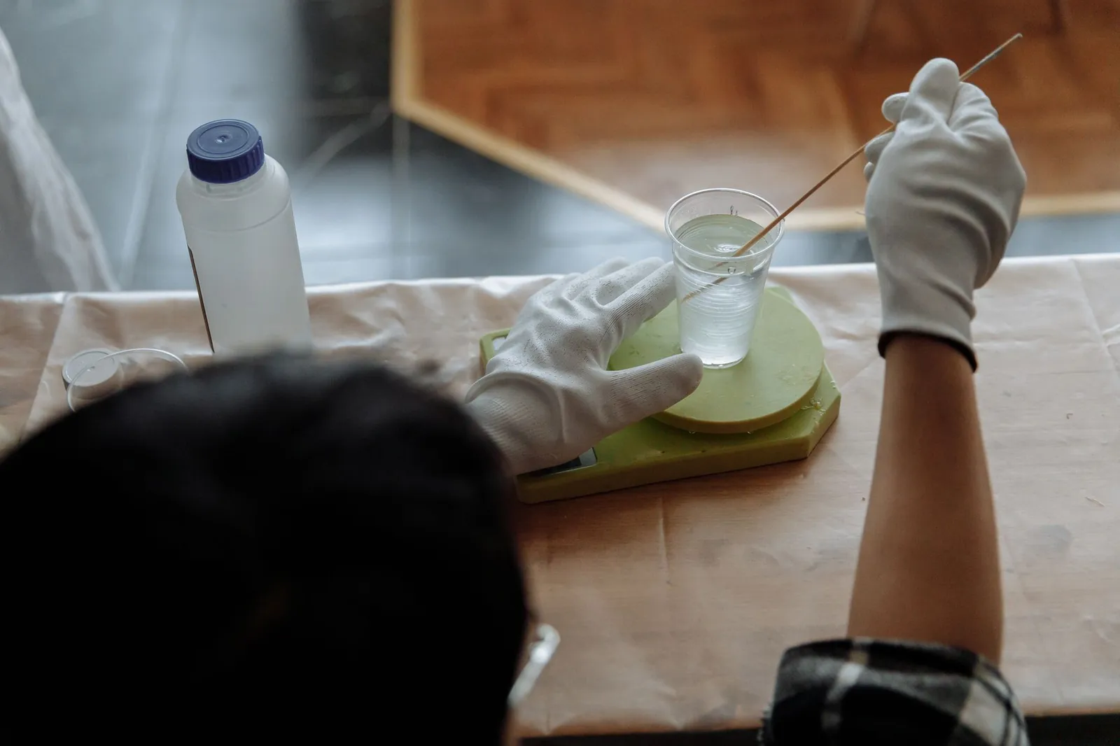 Close-up of a man mixing resin with gloves in an indoor workshop setting. Stock photo illustrating Century Plyboards (India)'s production started story.