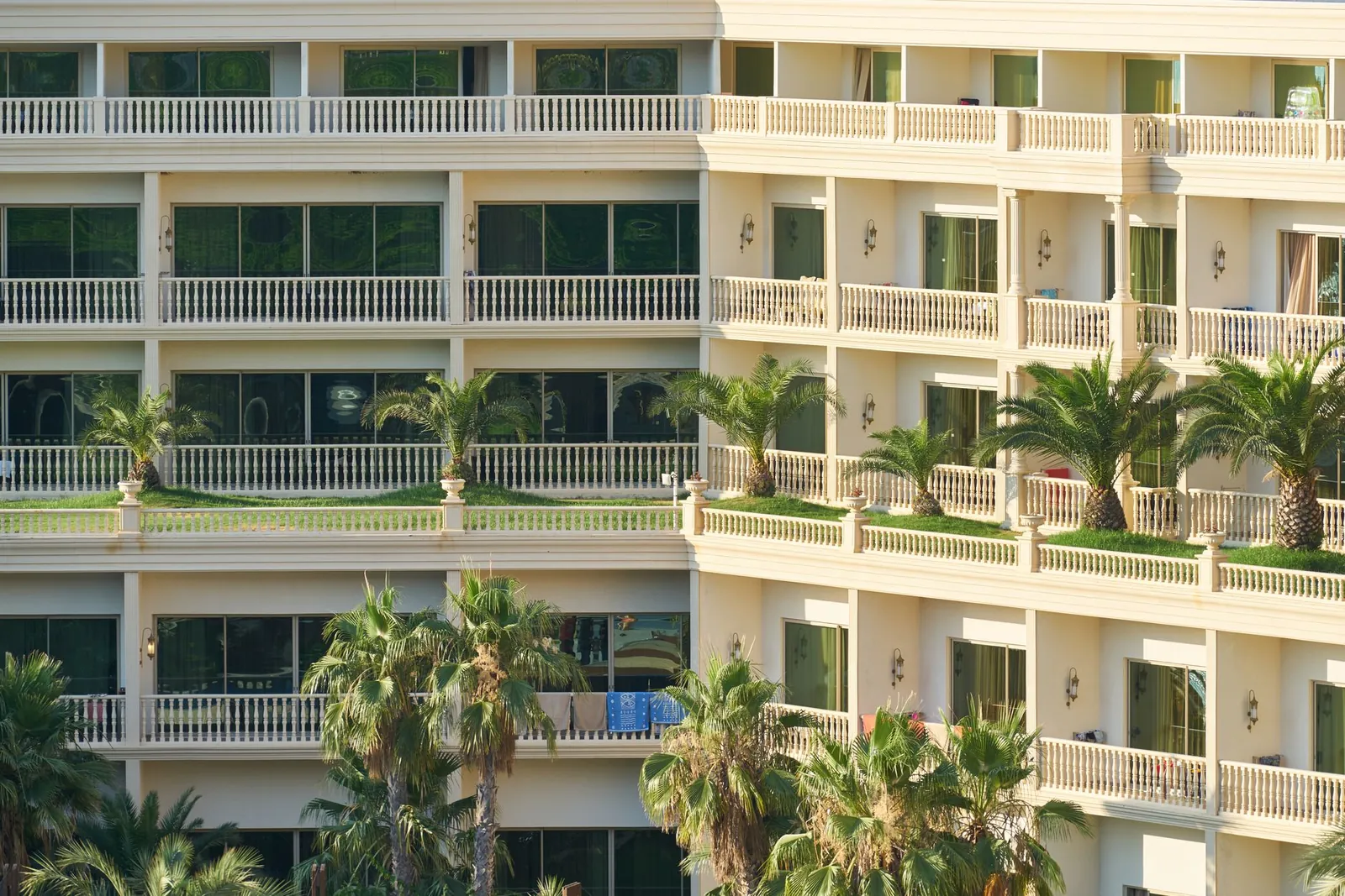 Elegant apartment building exterior with lush palm trees and balconies, ideal for vacation living. Stock photo illustrating Emerald Leisures' fund raise story.