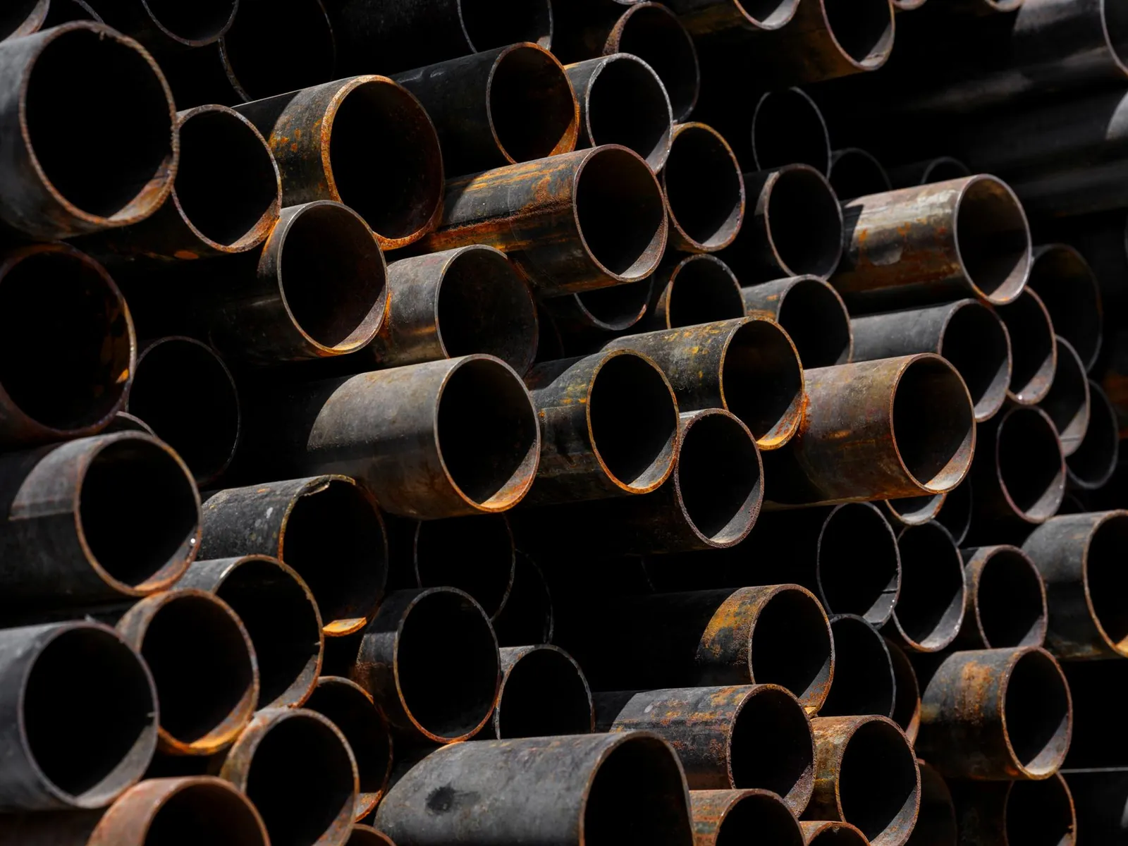 Close-up of stacked rusty pipes showcasing industrial recycling processes. Stock photo illustrating Rama Steel Tubes' fund raise story.