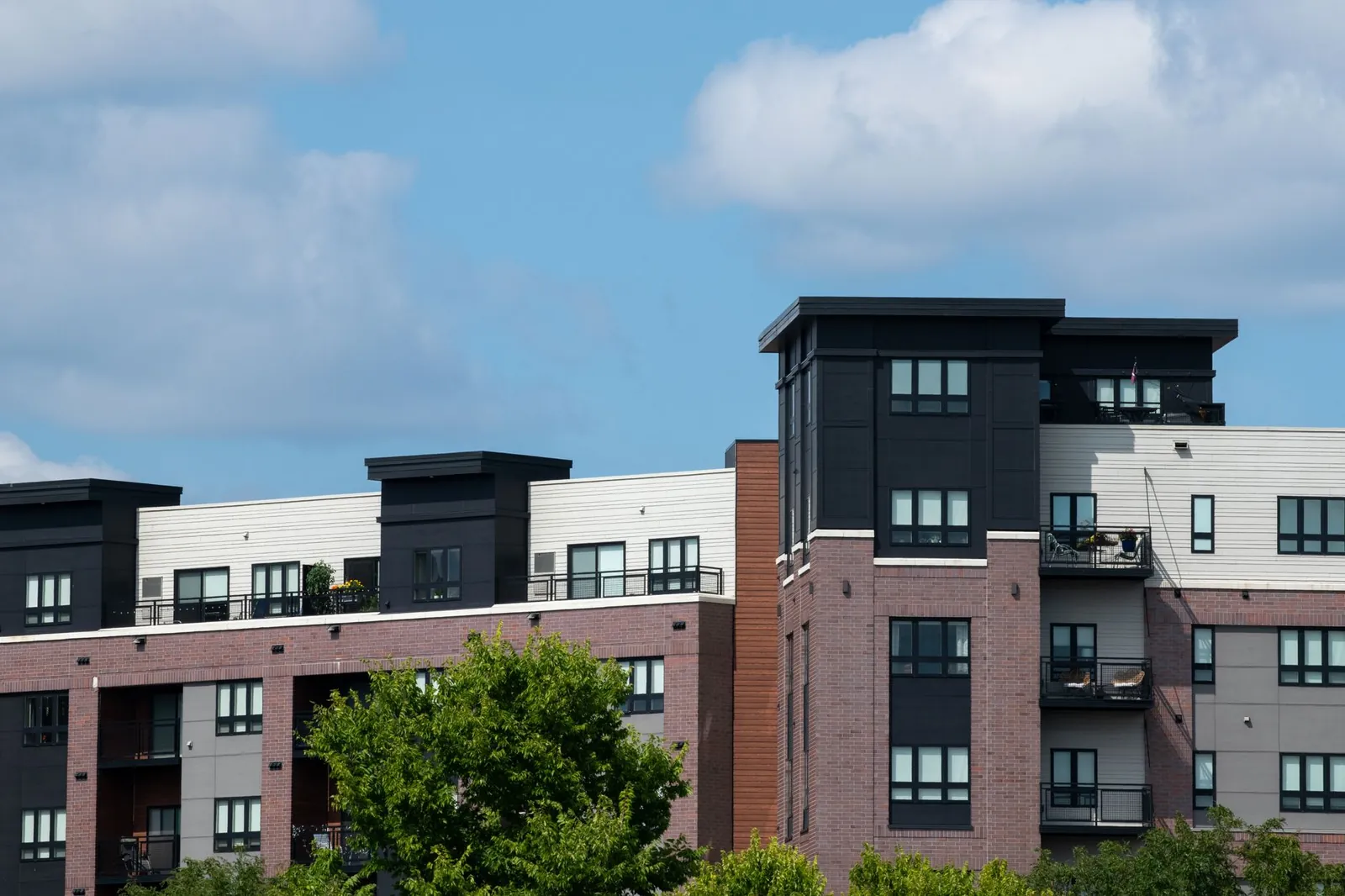 Contemporary urban apartment complex with brick and panel design under clear blue skies. Stock photo illustrating Arvind SmartSpaces' earning call story.